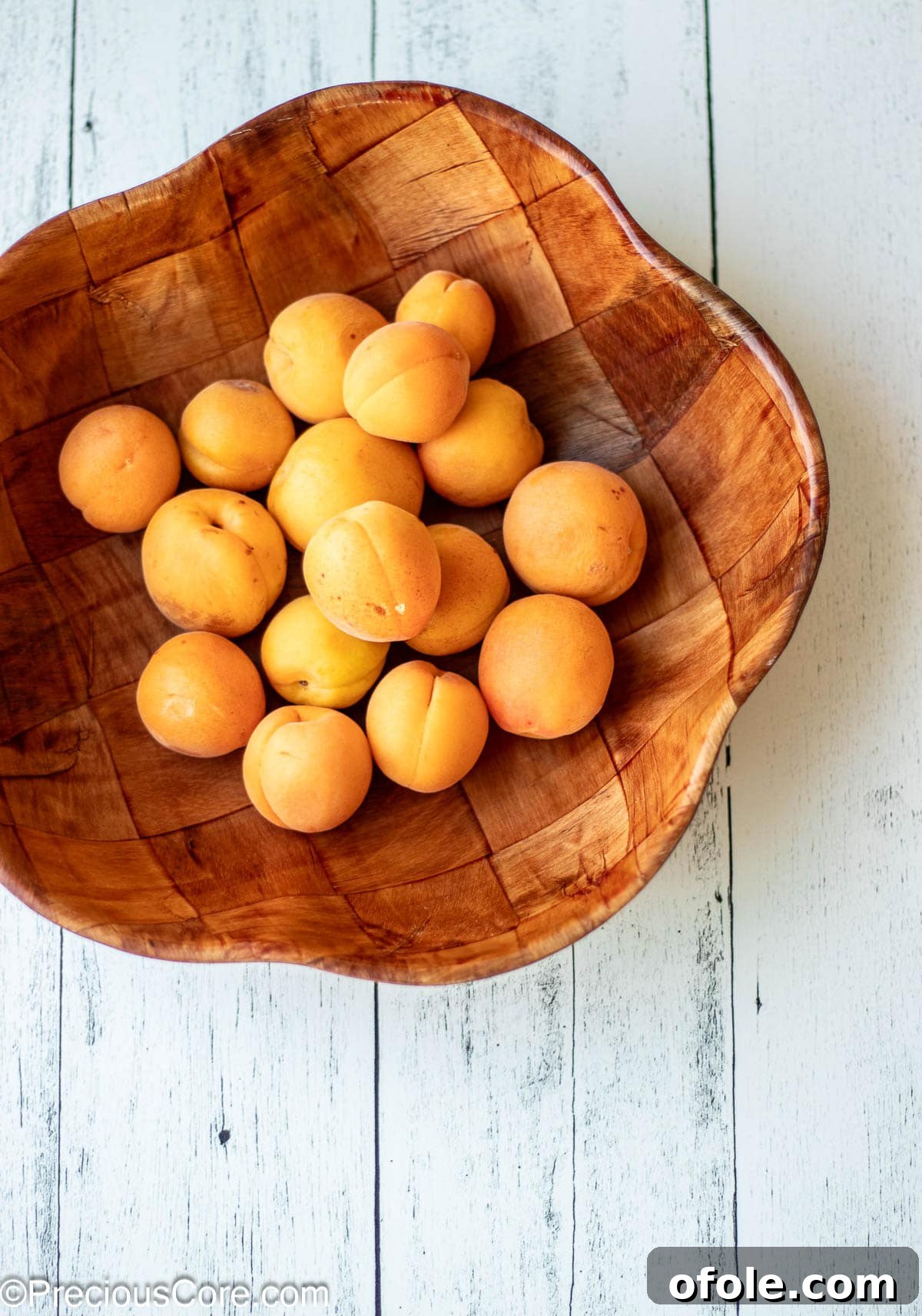A wooden bowl overflowing with fresh, vibrant apricots, symbolizing the bounty of the harvest.