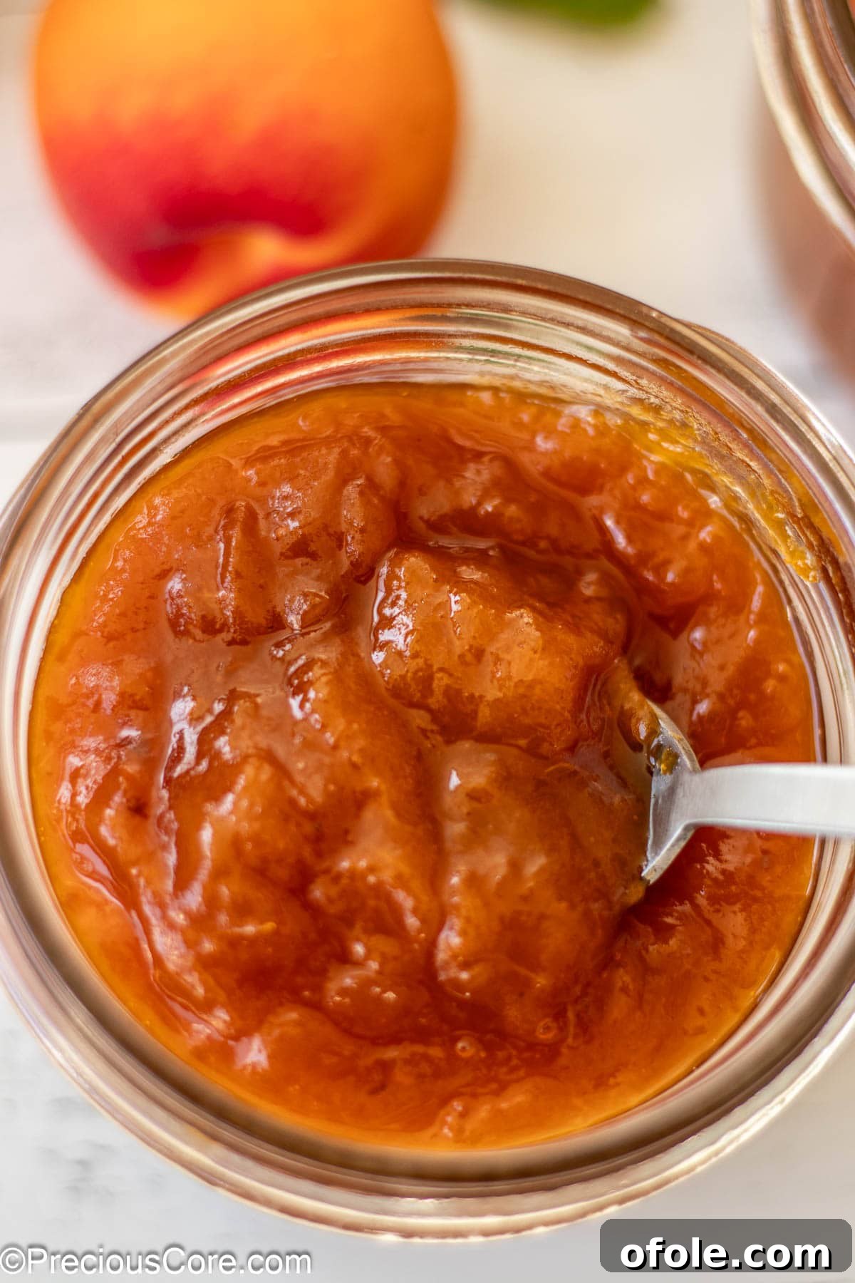 A close-up shot of golden apricot preserves gleaming inside a clear mason jar, highlighting their rich color and inviting texture.
