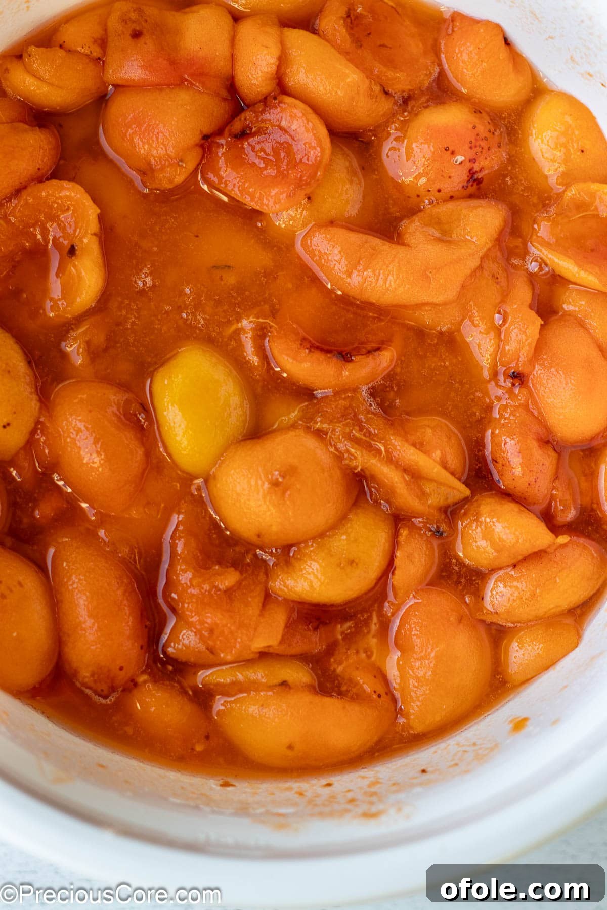 The liquidy mixture of apricots, sugar, and lemon juice in a bowl after macerating, showing the juices drawn out from the fruit.