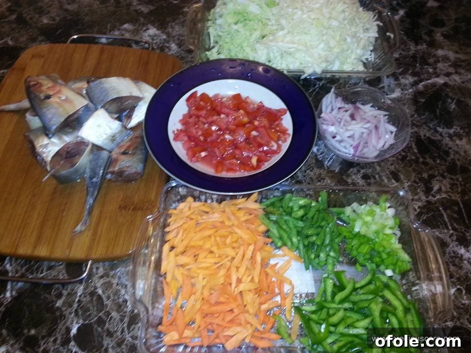 Assortment of fresh ingredients including fish, tomatoes, onions, and spices, ready for a flavorful Cameroon mixed vegetable recipe.