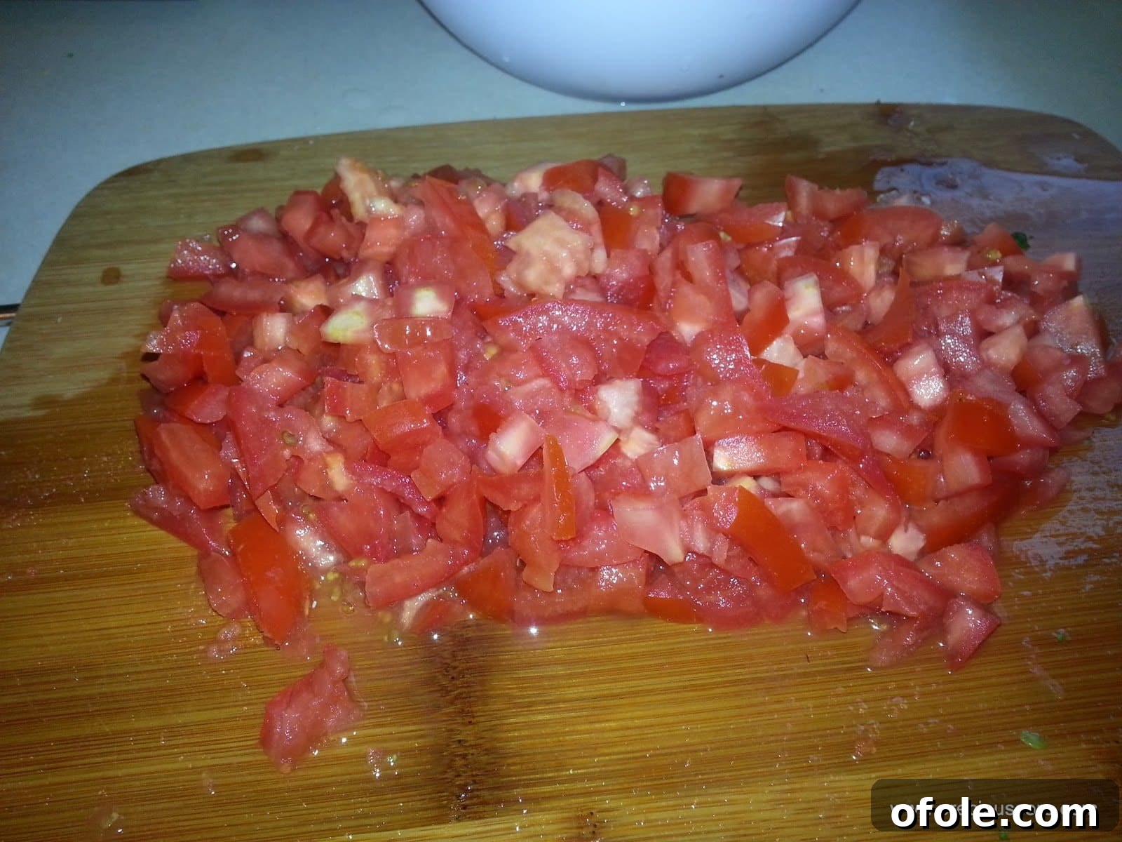 Diced fresh tomatoes, meticulously prepared and ready to be added to the cooking pot for the mixed vegetable stir-fry, forming a vibrant base.