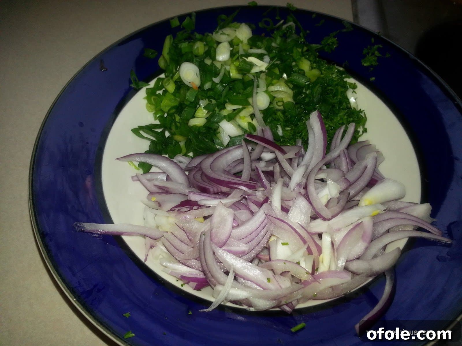 Finely chopped onions and fresh green herbs (celery, parsley, green onions) for an aromatic and flavorful base, ready for cooking.