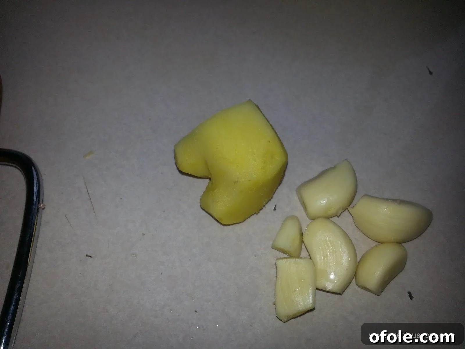Peeled cloves of garlic and a piece of fresh ginger root, meticulously prepared and ready for grating or mincing, essential aromatics.
