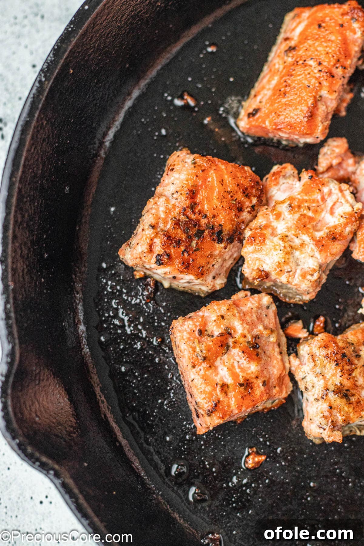 Irresistible Salmon Bites 3 Cubed salmon pieces in a cast iron skillet, ready for searing.