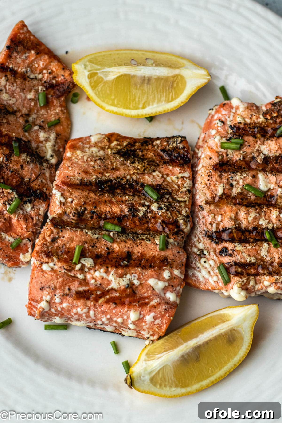 Grilled Sockeye Salmon steaks on a white plate, garnished with fresh herbs.
