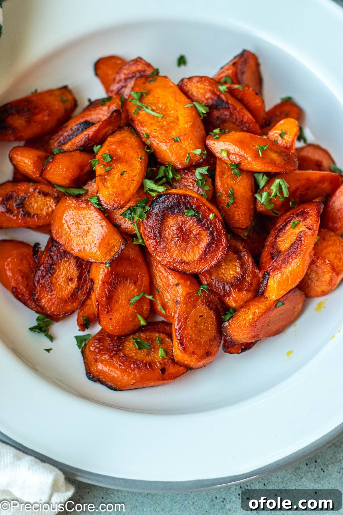 Caramelized Carrots 7 Carrots on a white plate garnished with parsley.