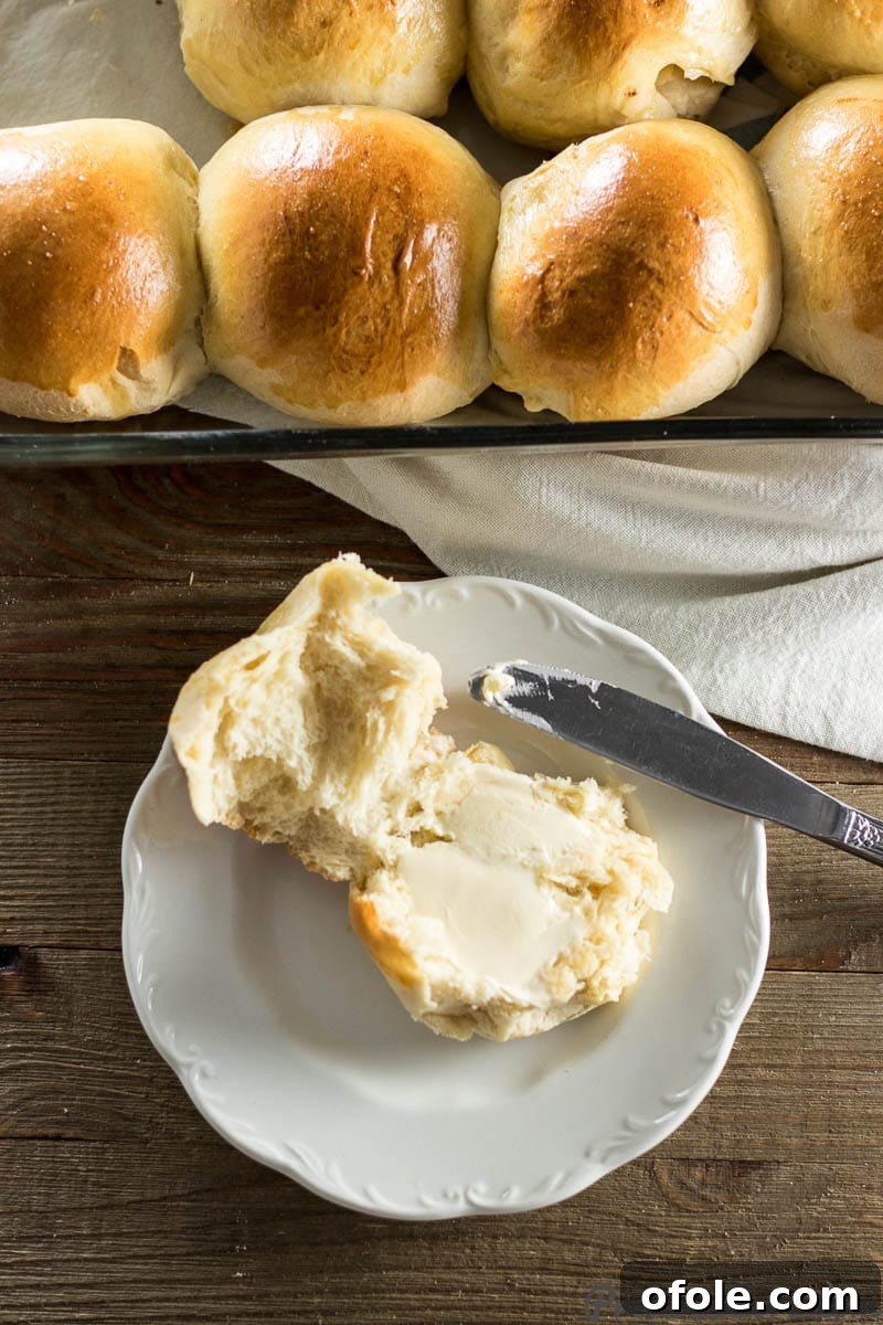 Two sweet dinner rolls served with a dollop of butter on a wooden board.