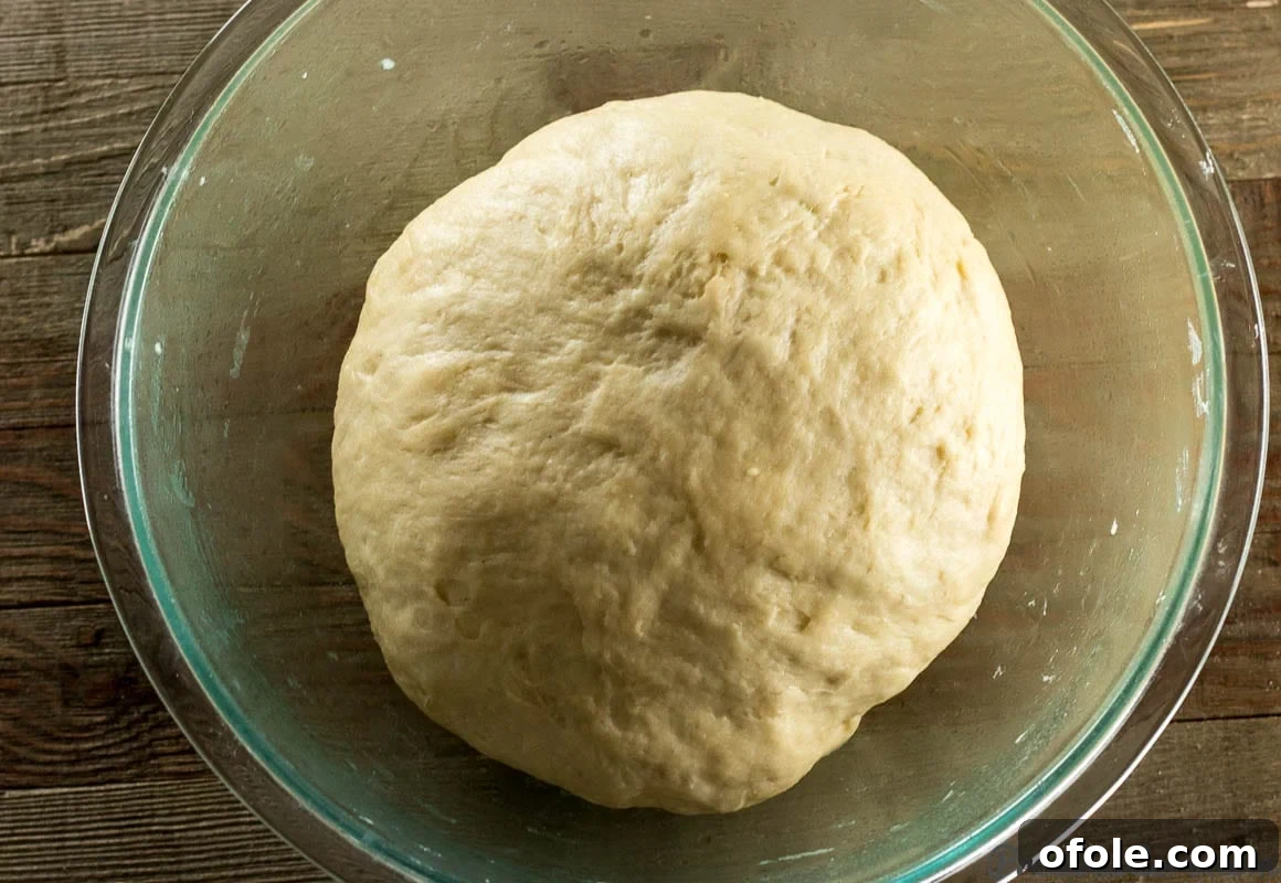 Sweet dinner roll dough after its first rise, having doubled in size within a glass bowl.