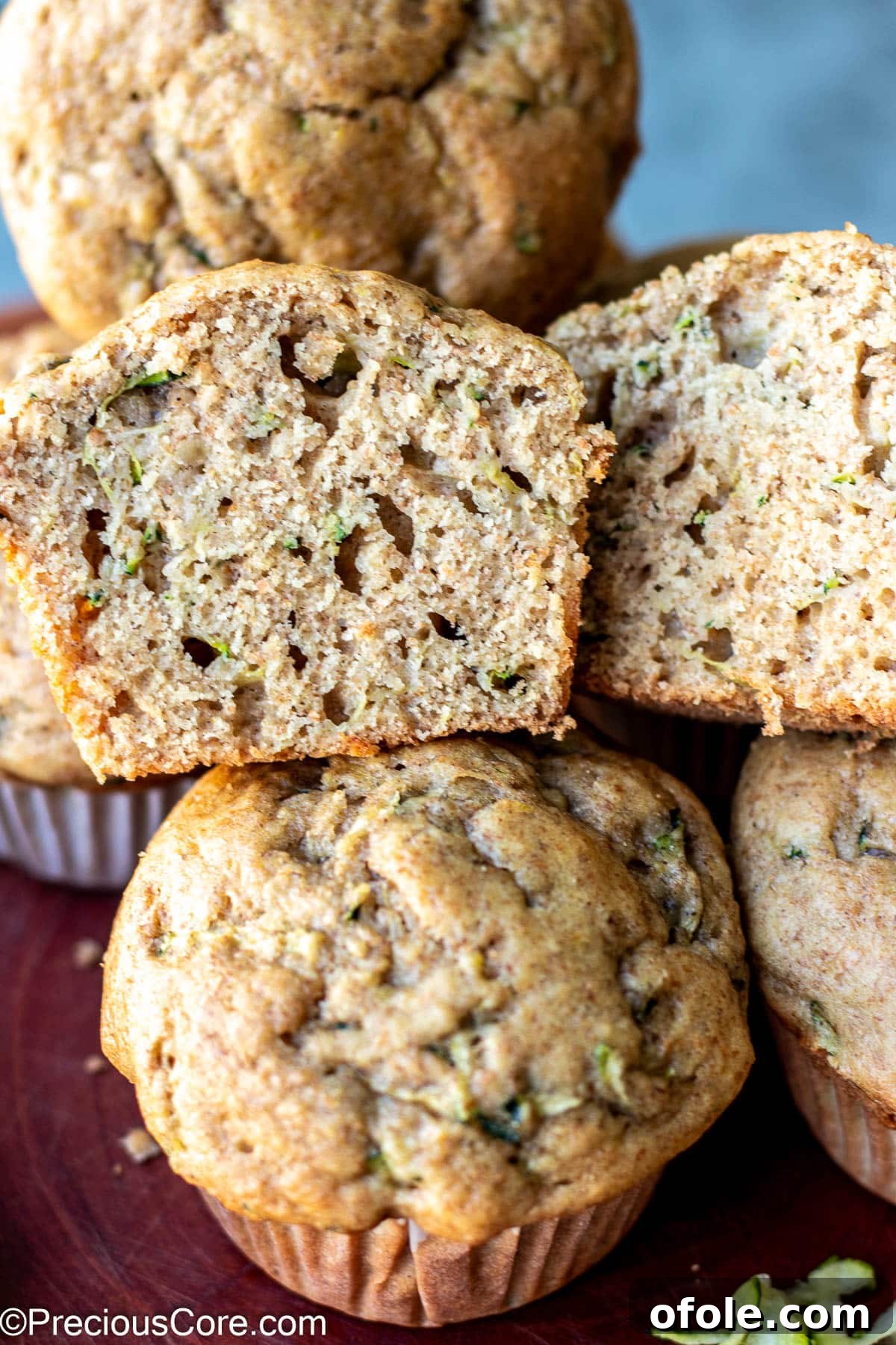 Zucchini muffin cut in half to show its soft, fluffy texture with specks of zucchini.