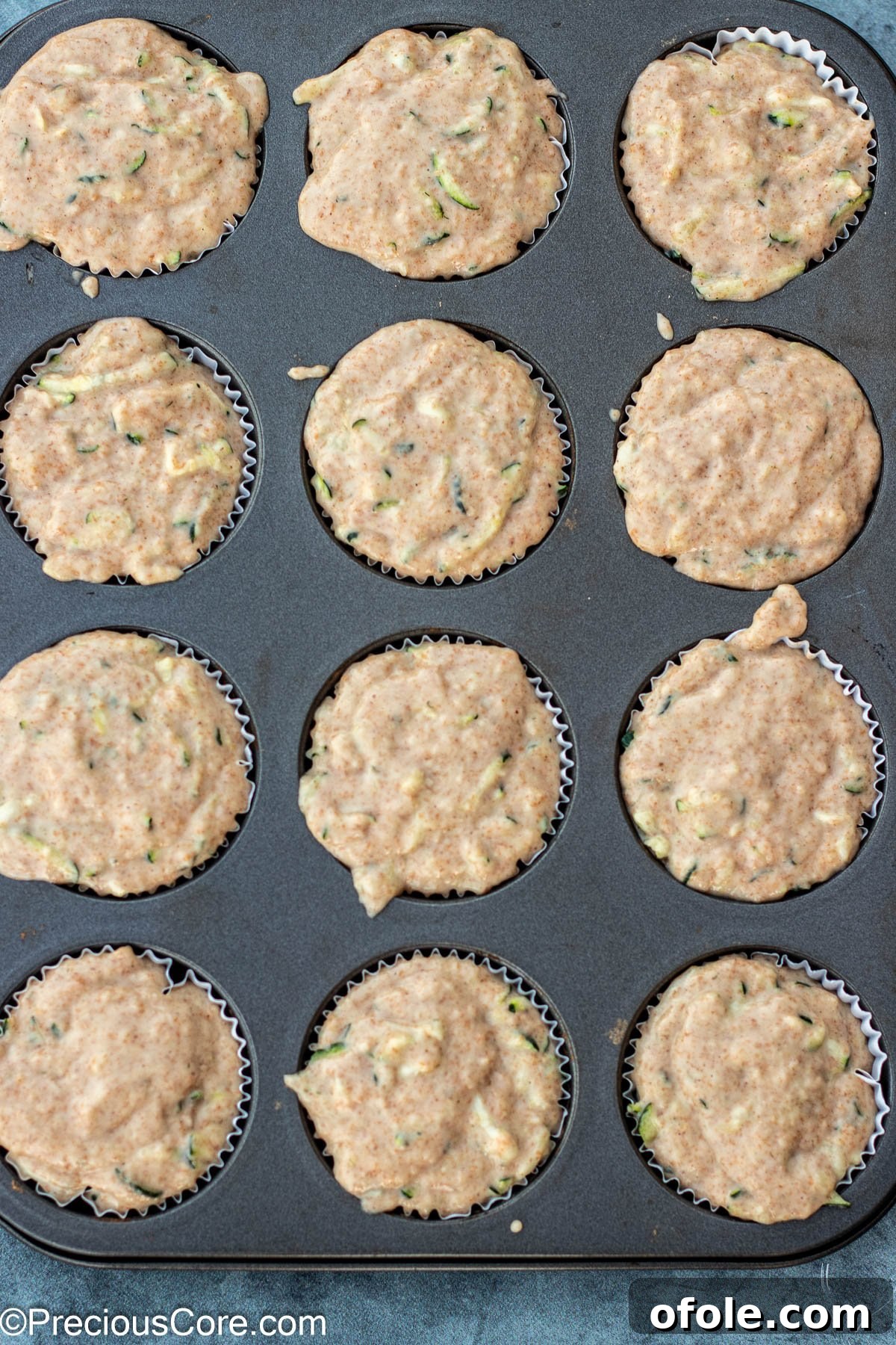Zucchini muffin batter scooped into a muffin tin, ready for baking.