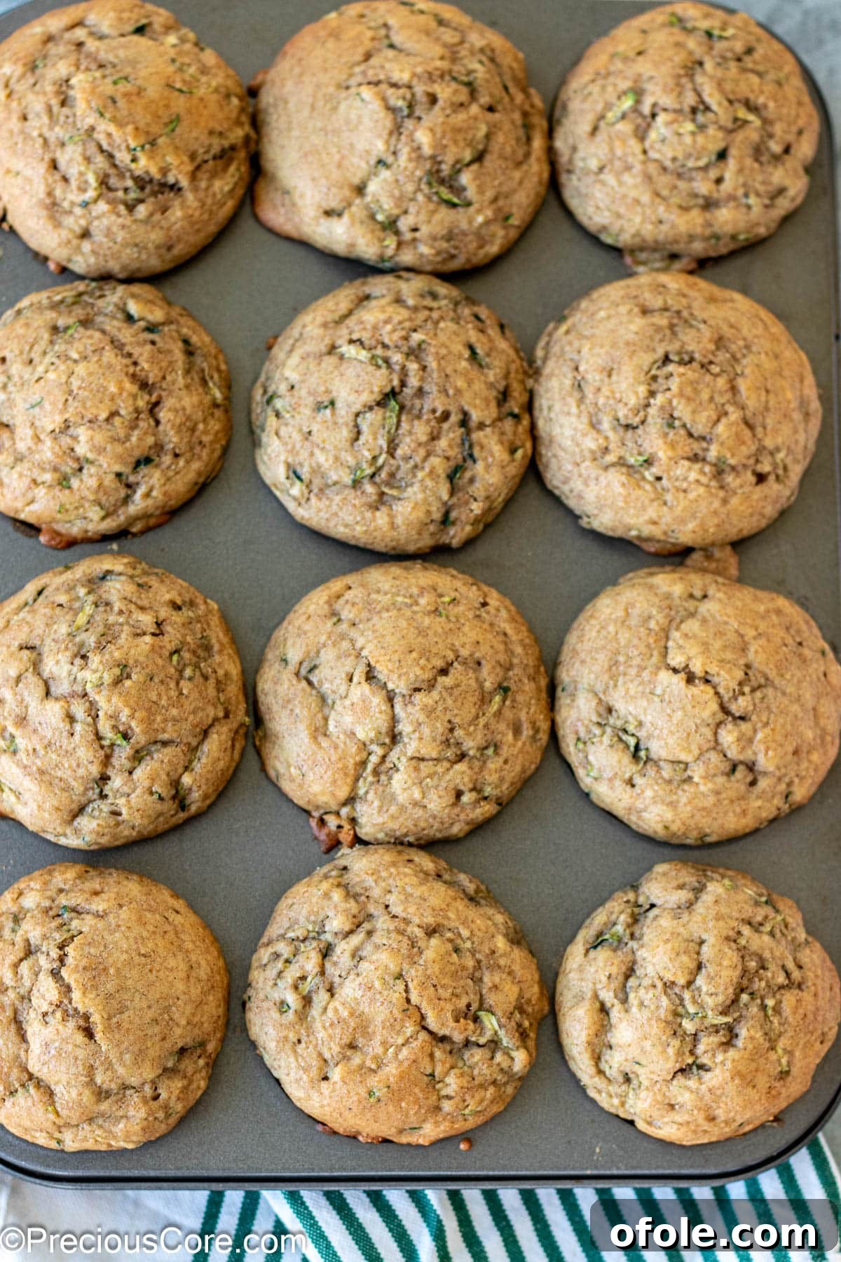 Freshly baked zucchini muffins with applesauce in a muffin tin, golden brown and perfectly risen.