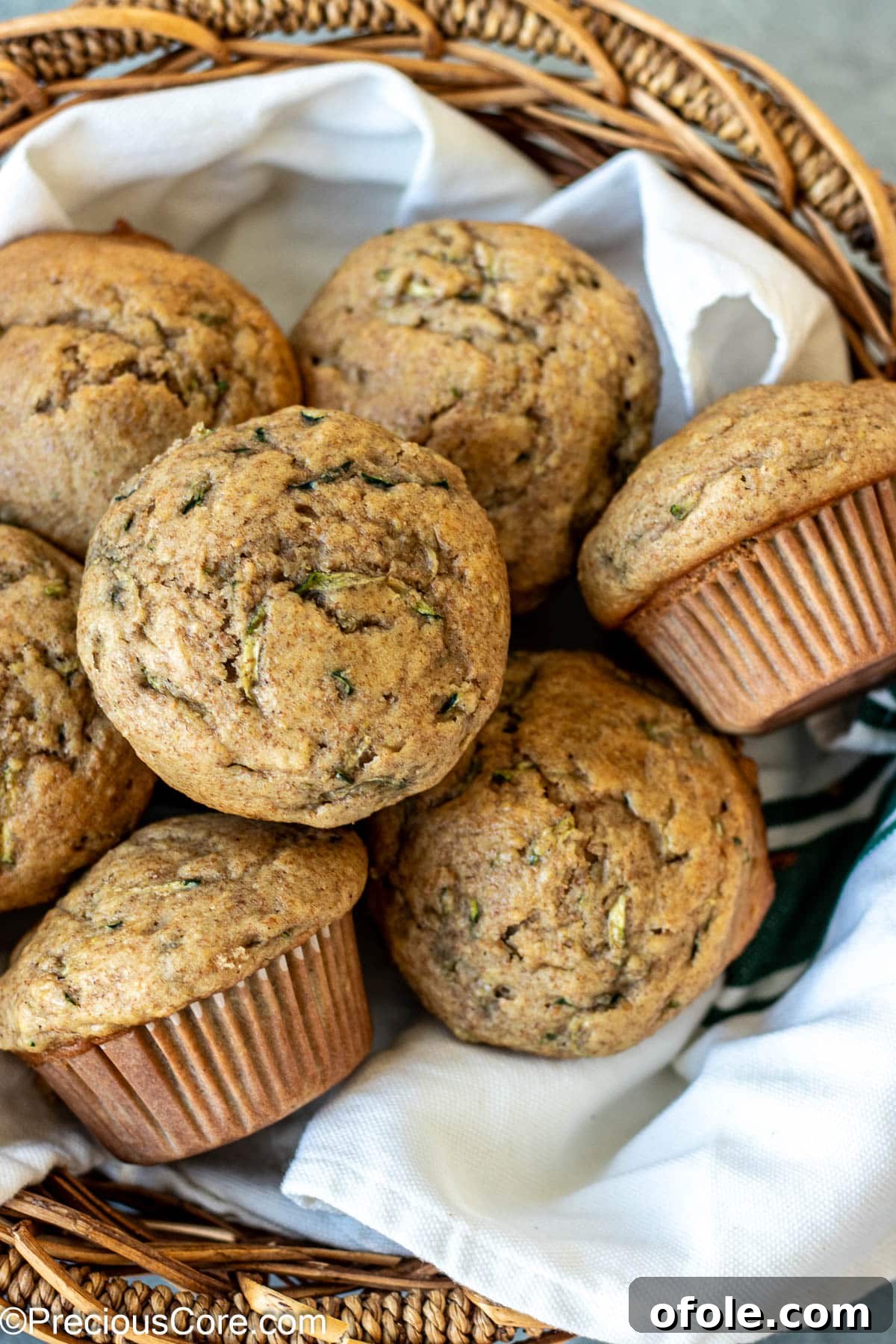 Freshly baked zucchini muffins arranged beautifully in a basket lined with a kitchen cloth.