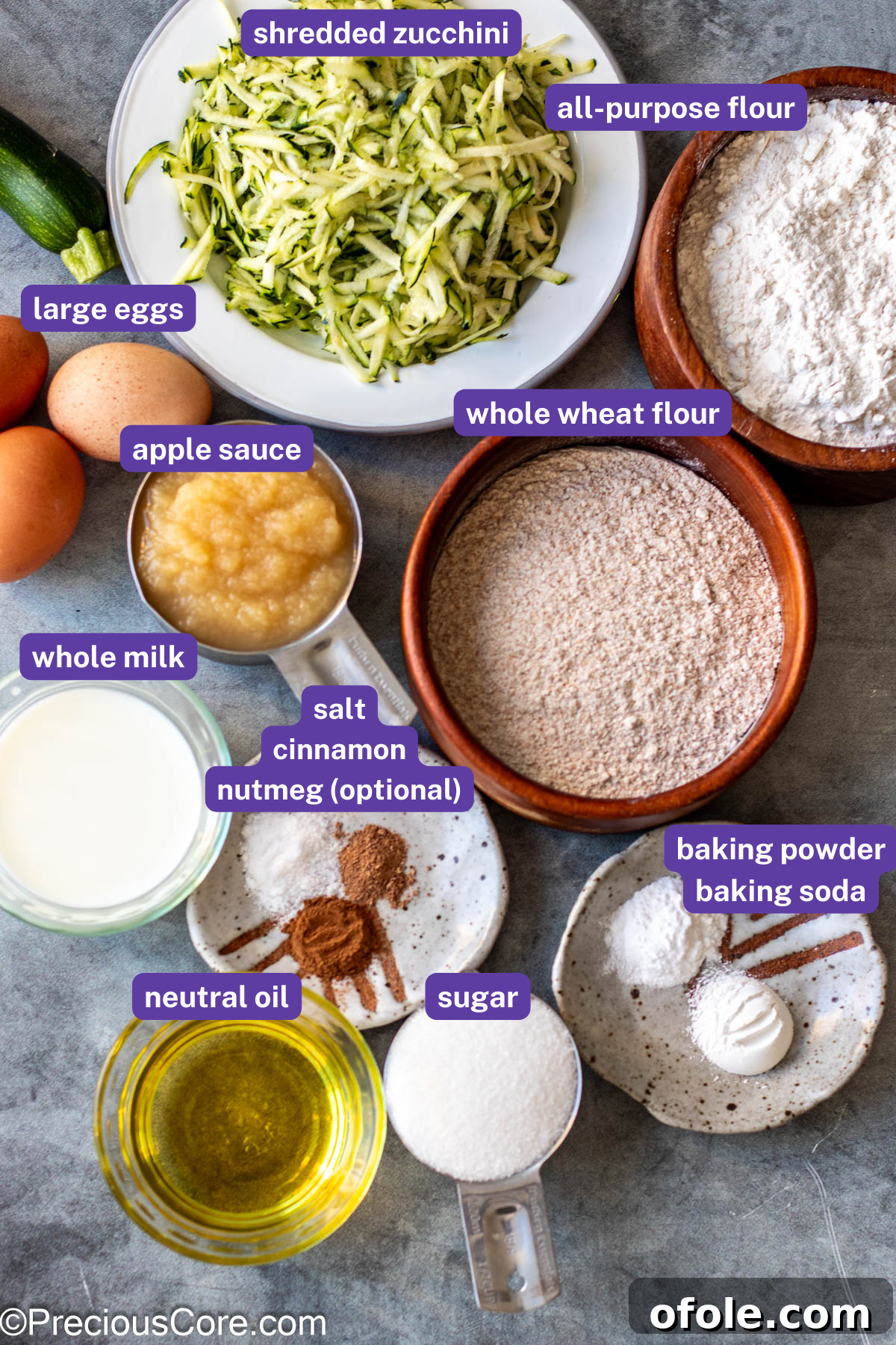 All ingredients for zucchini muffins laid out on a table with individual labels.