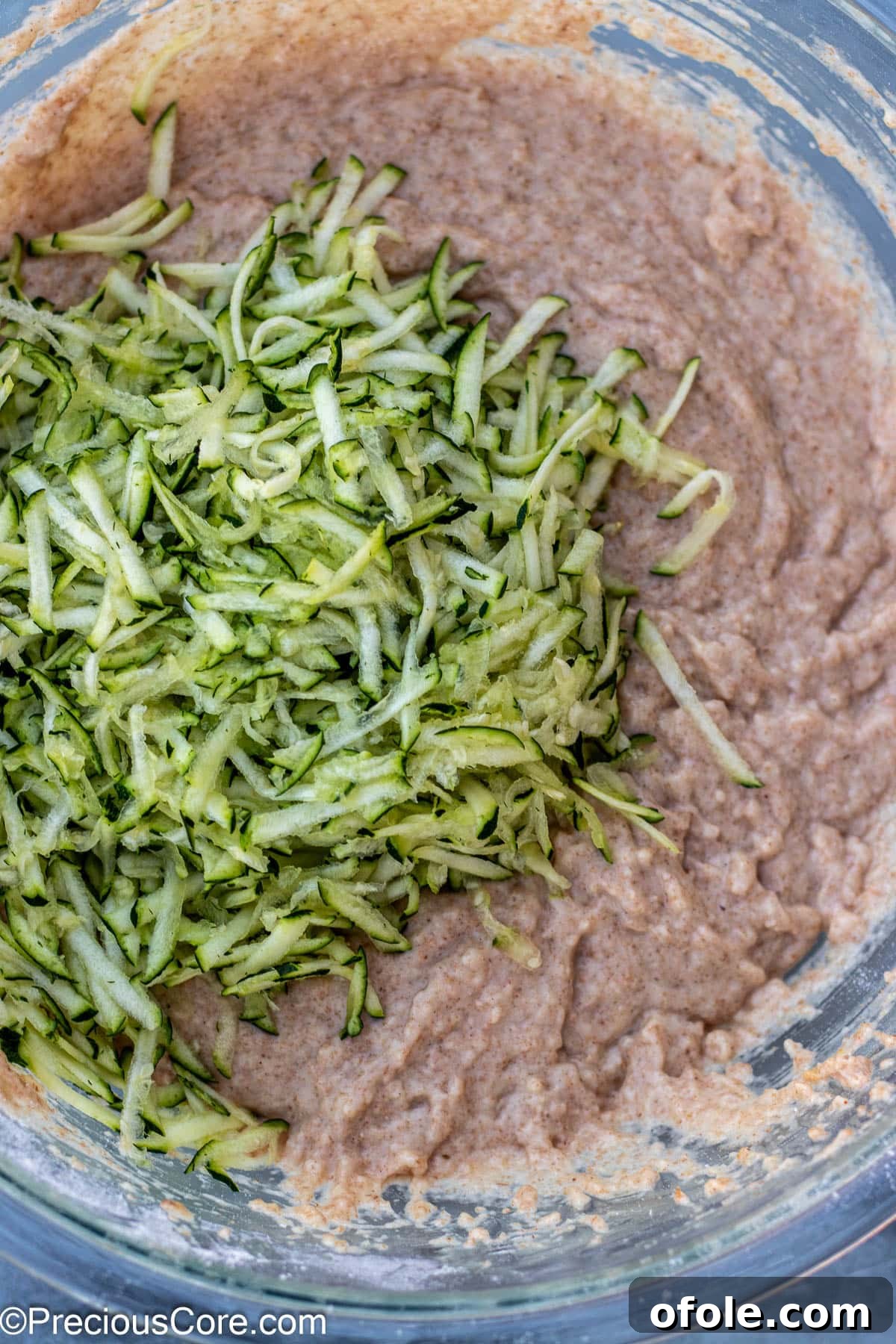 Shredded zucchini being added to the muffin batter.