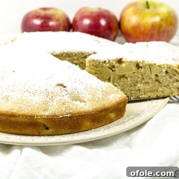 Old fashioned apple cake with a slice being removed, showing the moist interior.