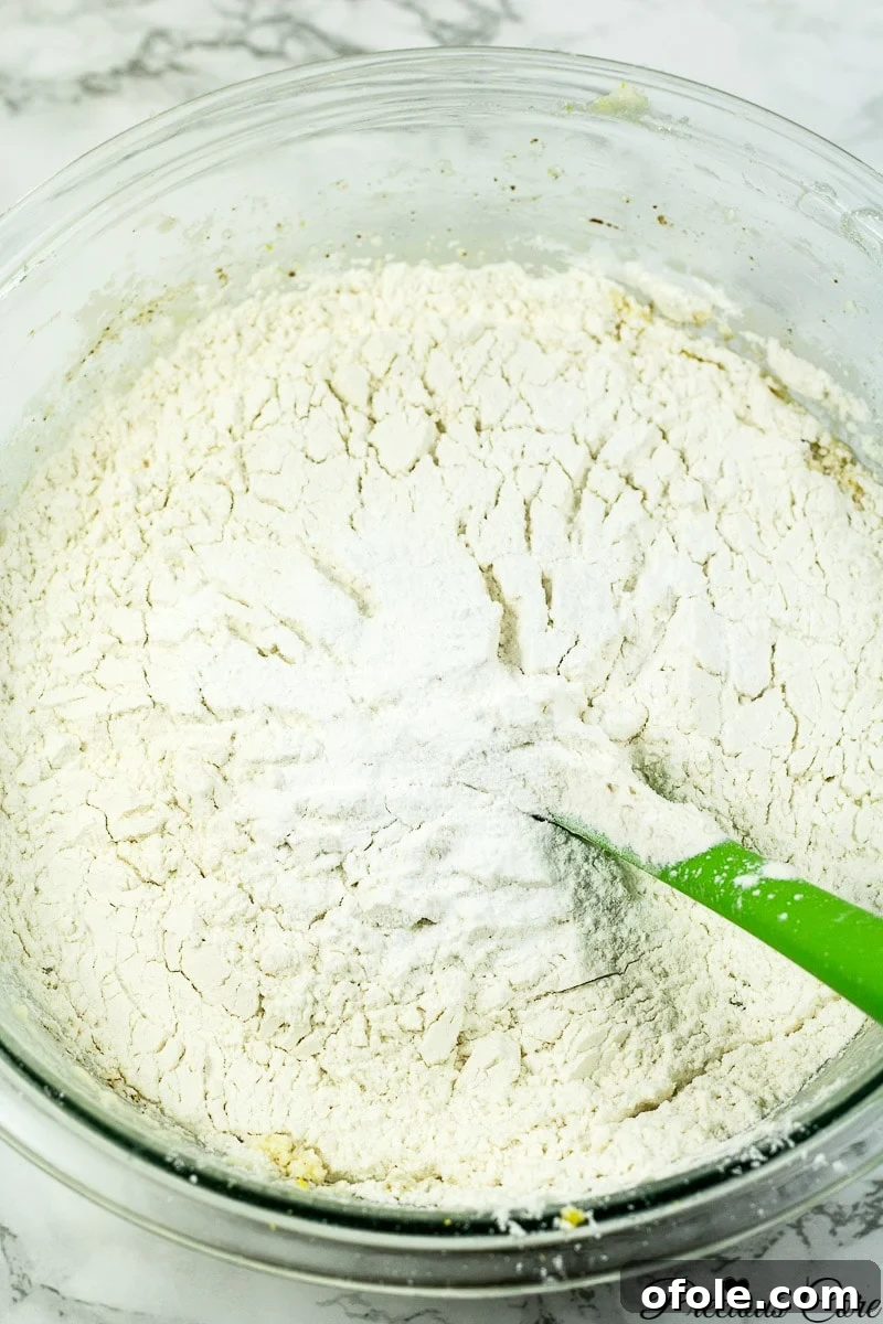 Timeless Fresh Apple Cake 10 The dry ingredients, including flour, baking powder, and salt, being mixed into the wet batter.