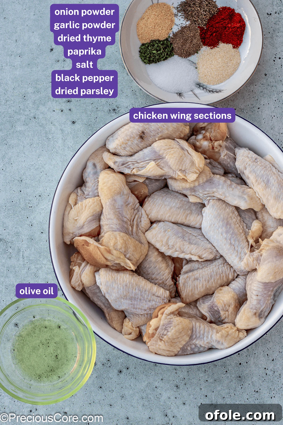 A flat lay image showing all the essential ingredients for dry rub chicken wings: chicken wings, olive oil, and various spices in small bowls.