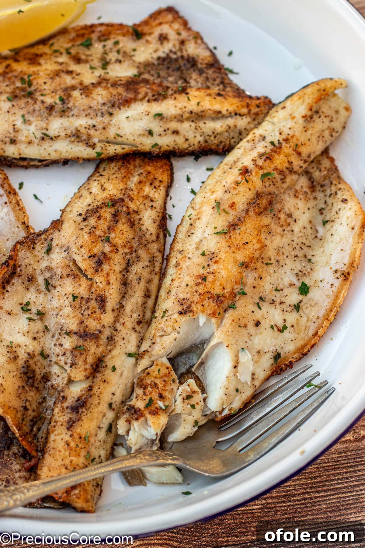 Fork flaking cooked sea bass to show its tender, flaky texture.