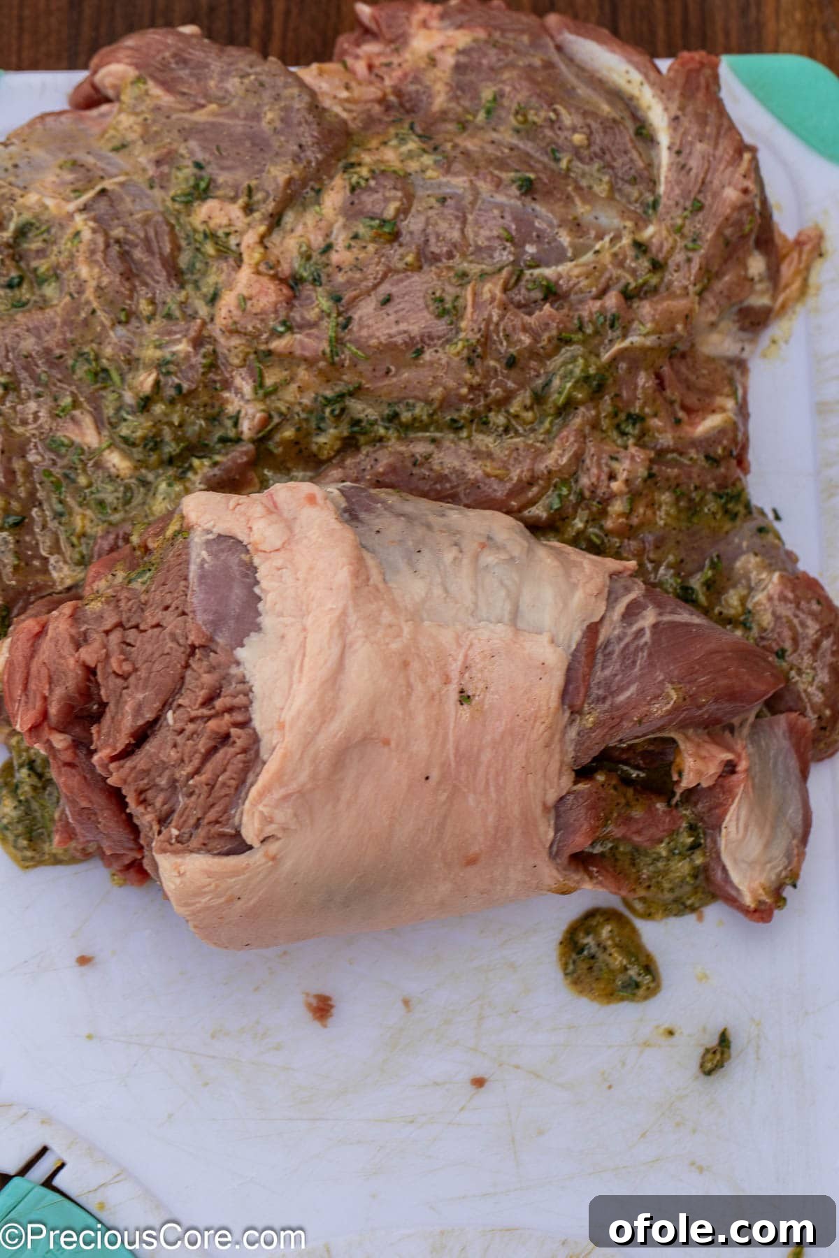 The process of rolling a butterflied boneless lamb leg into a compact log shape.