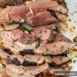 A sliced roasted boneless leg of lamb, garnished and ready to serve.