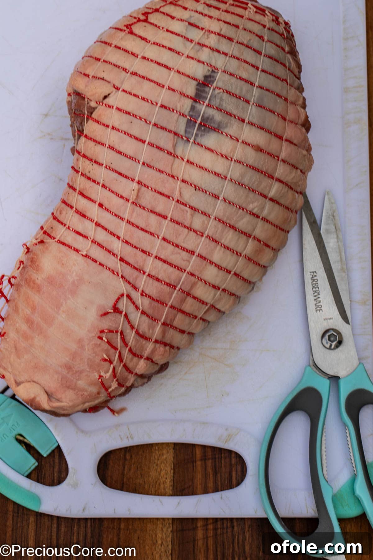 Carefully cutting off the netting from a boneless leg of lamb package.