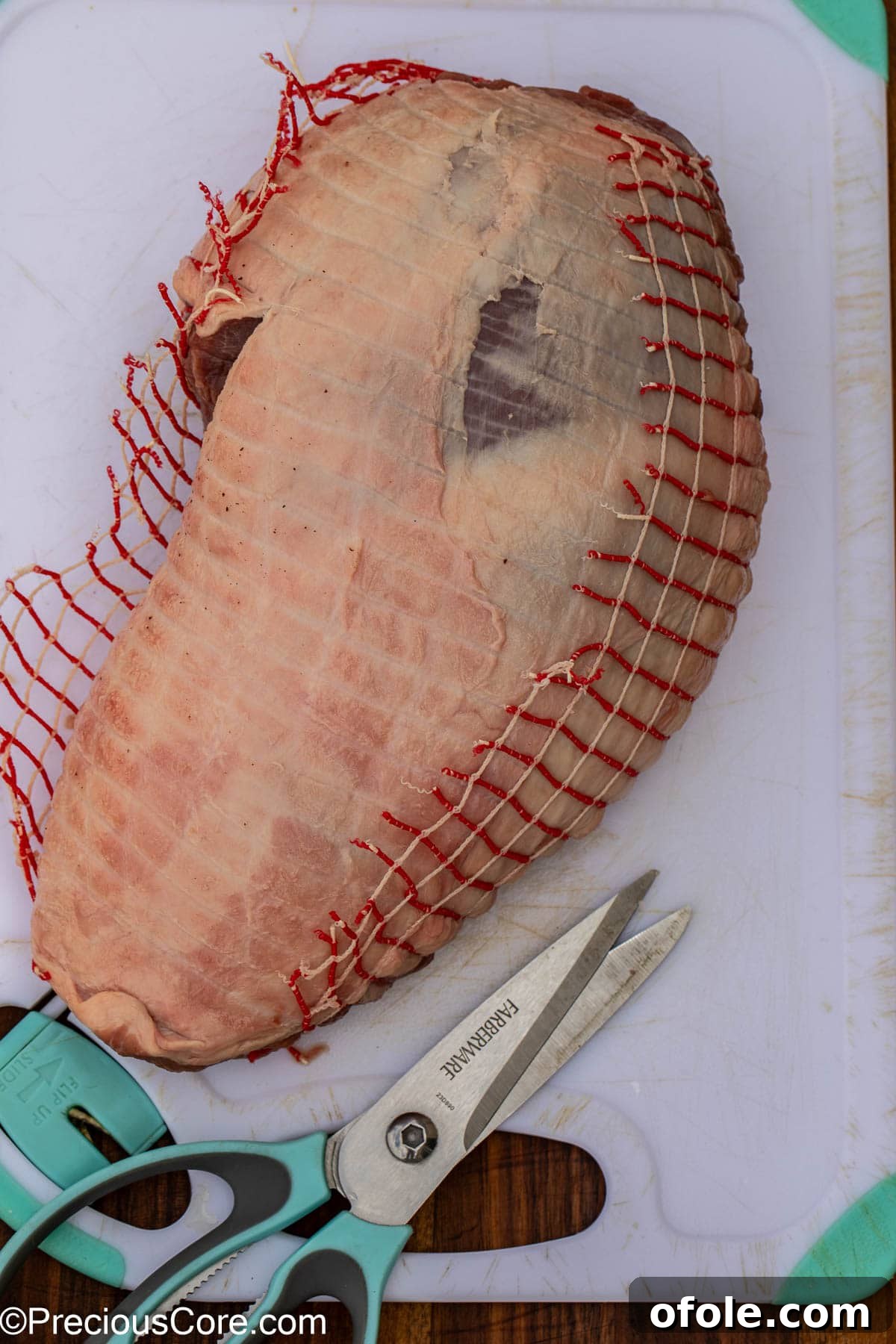 Removing the protective netting from a leg of lamb roast.