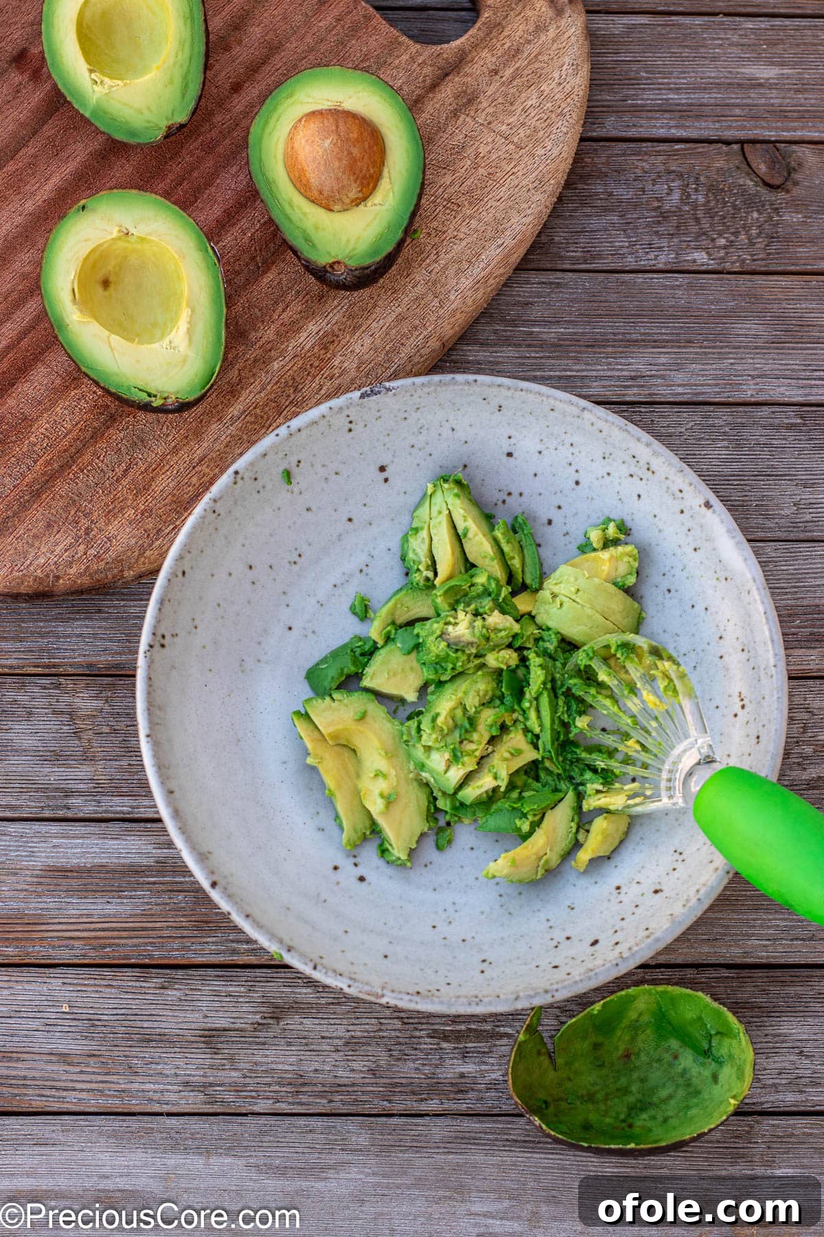 Perfectly scooped avocado halves, their bright green flesh showcased in a clean white bowl, ready for mashing and seasoning into guacamole.
