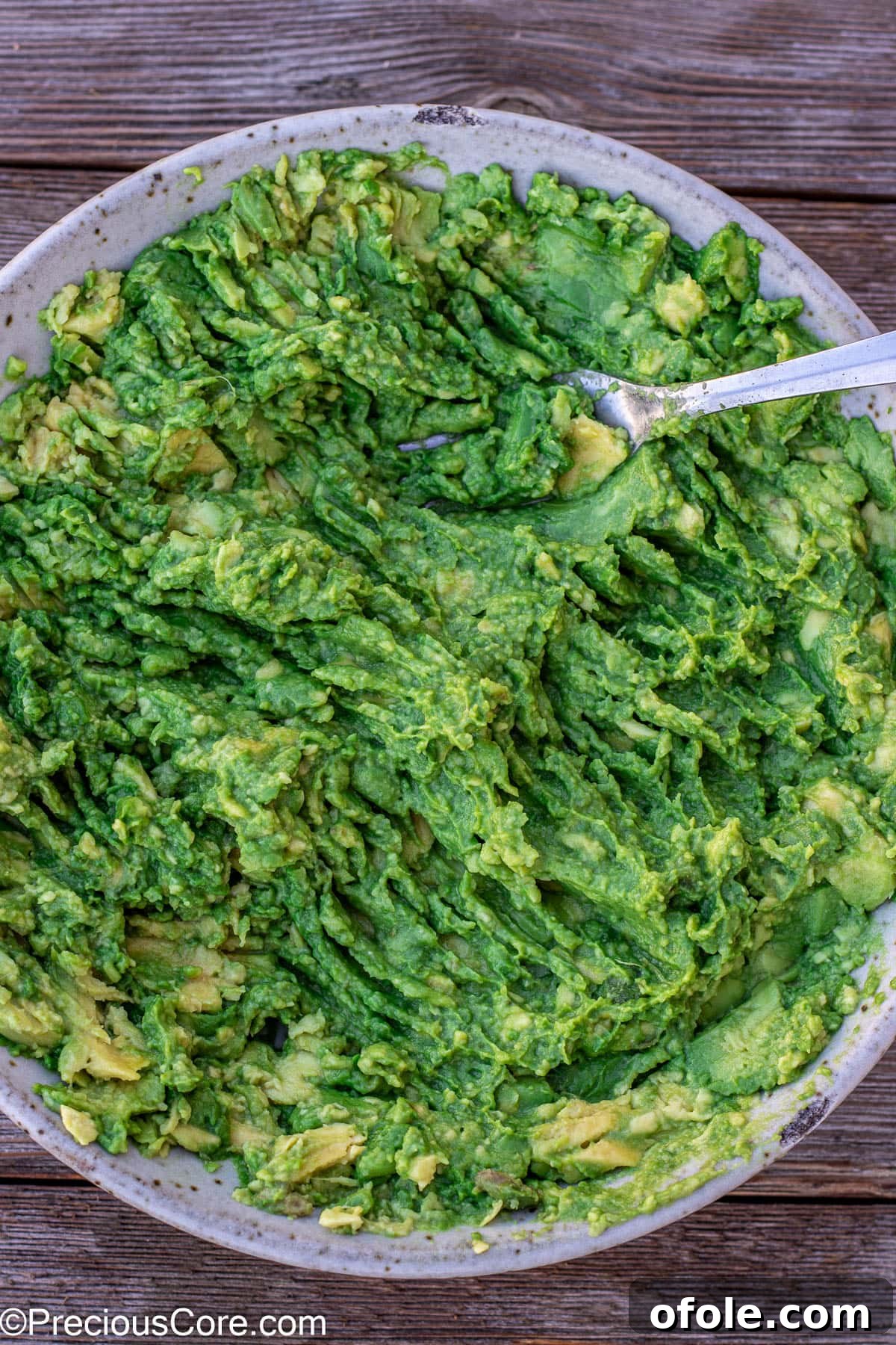 Close-up of mashed avocados in a bowl, showing a delightful chunky yet creamy texture, ideal for a homemade guacamole.