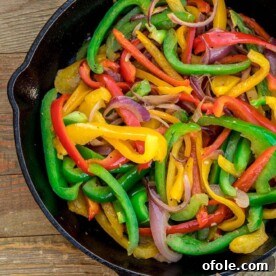 A vibrant mix of freshly sautéed bell peppers and onions, cooked to perfection in a cast iron skillet.