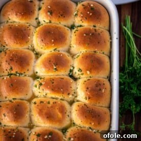 A full baking dish of golden-brown dinner rolls, glistening with a fresh brushing of garlic butter.