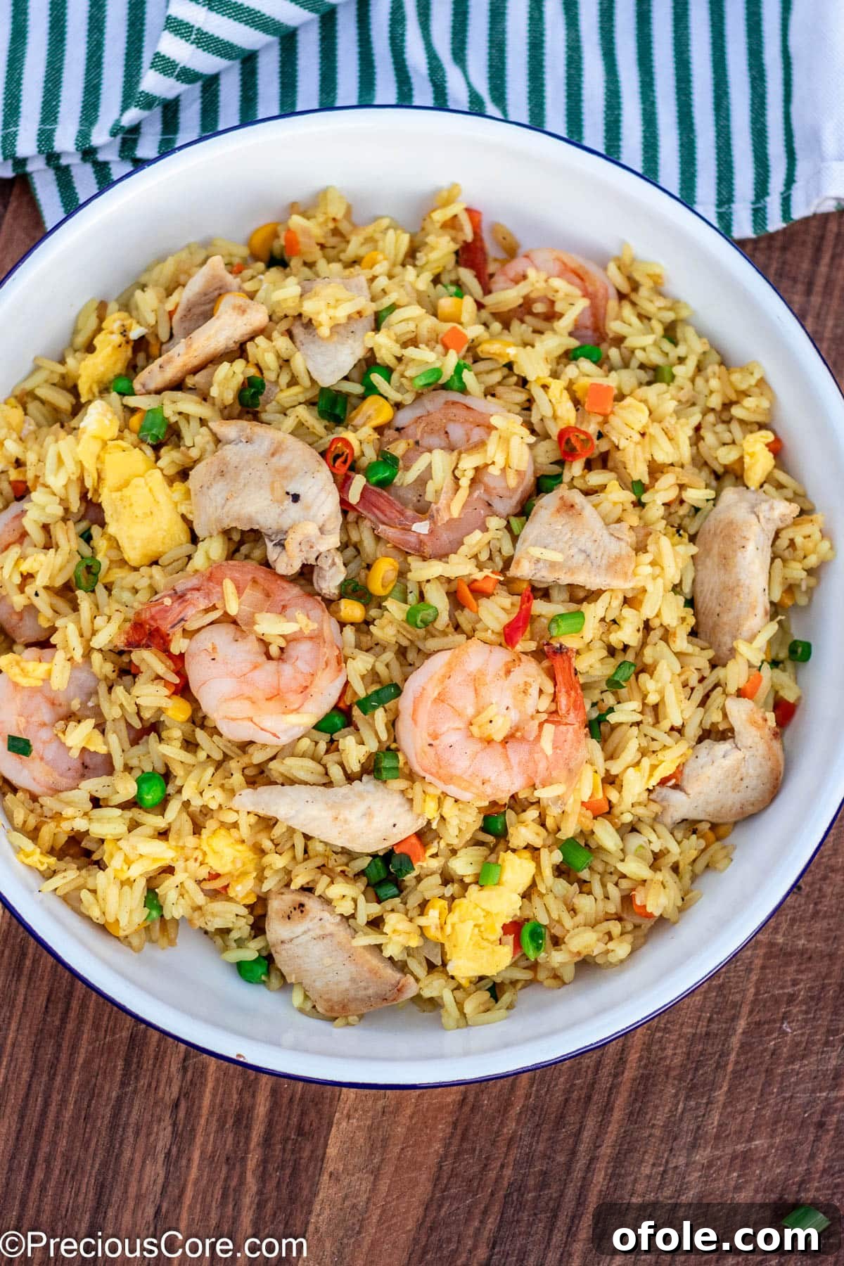 Signature Surf & Turf Fried Rice 3 Fried rice in a plate, topped with chicken and shrimp, garnished.