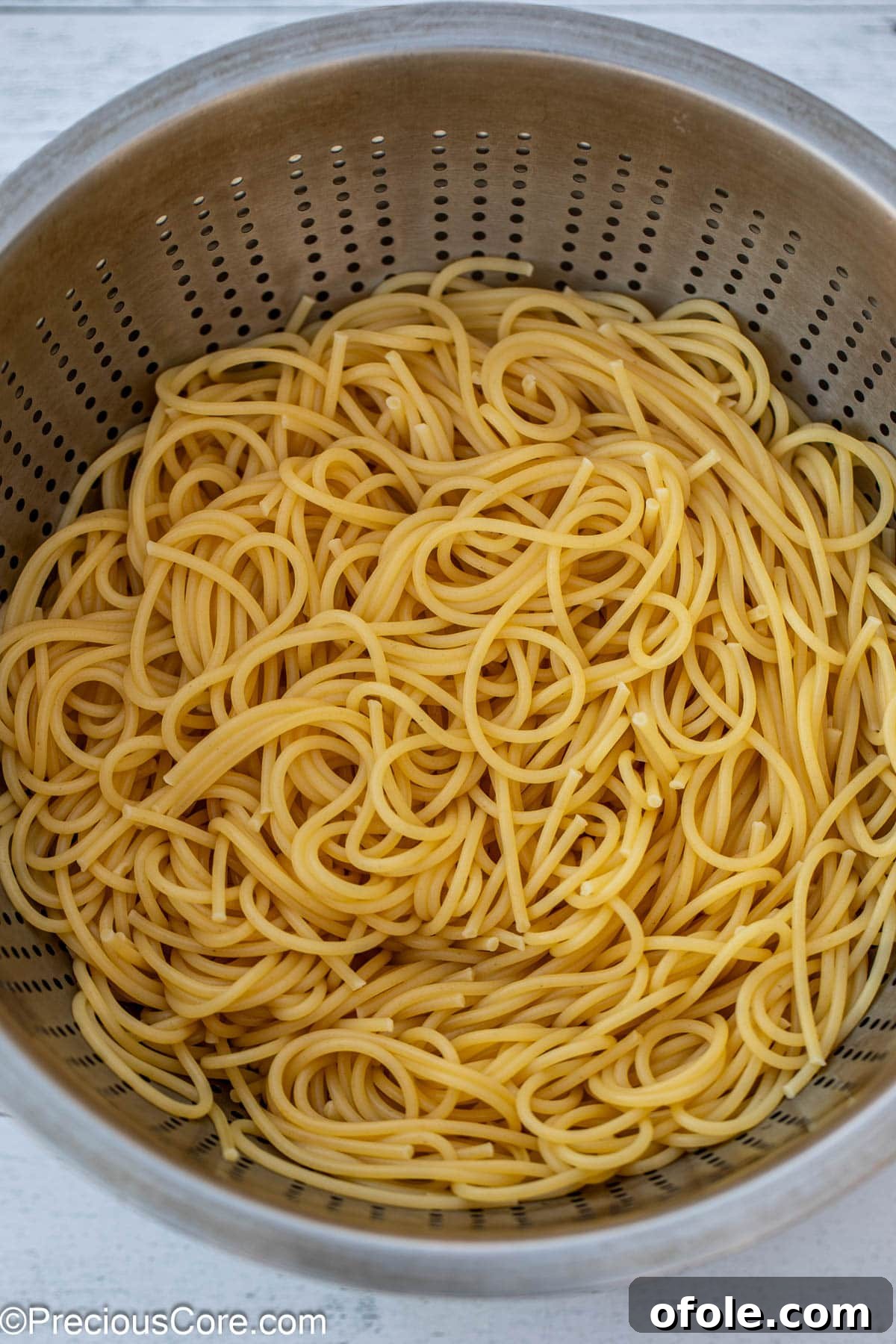 Perfectly cooked and strained spaghetti resting in a metal colander after boiling.