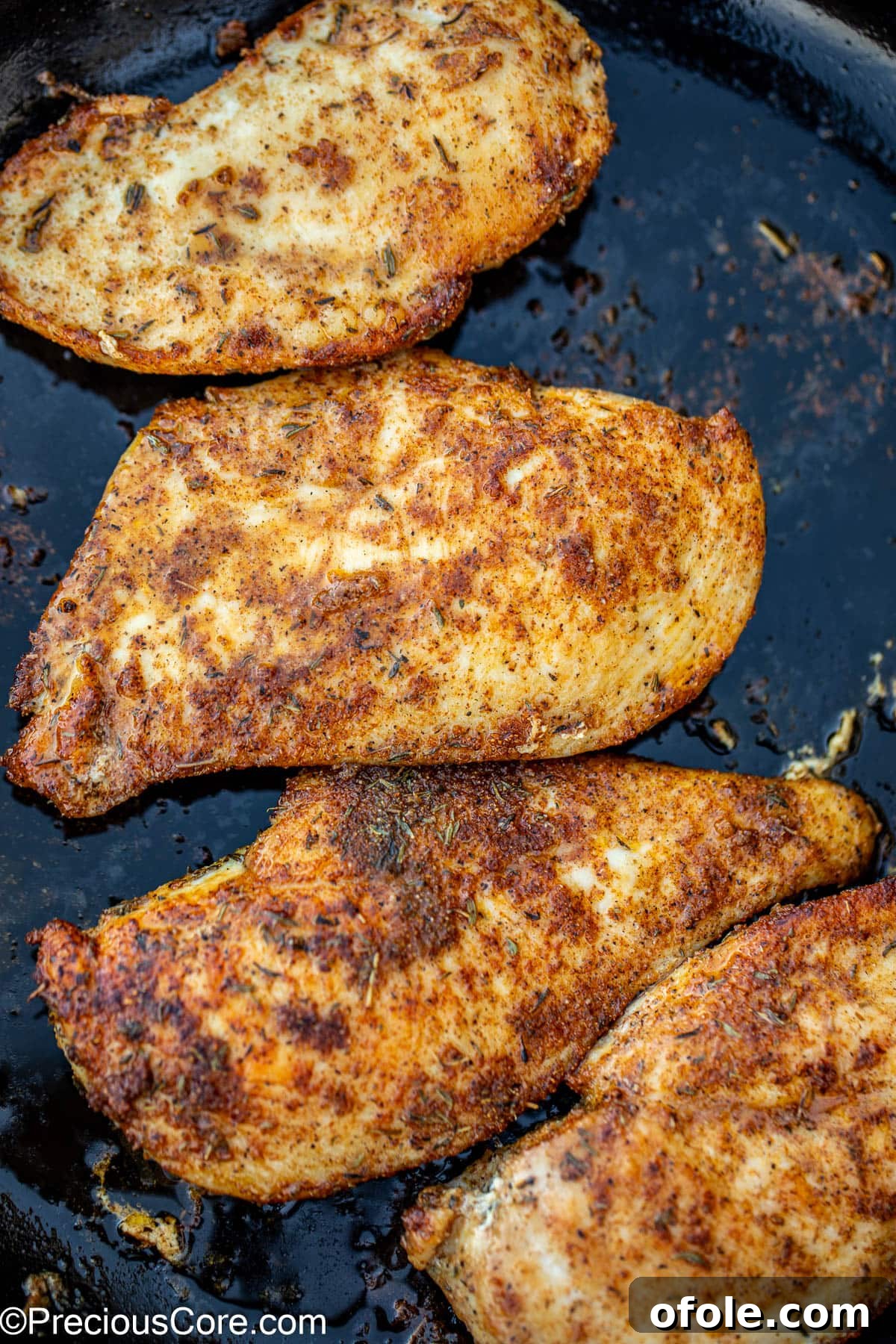 Golden-brown pan-seared chicken breasts cooking in a hot skillet, showcasing a perfect crust.