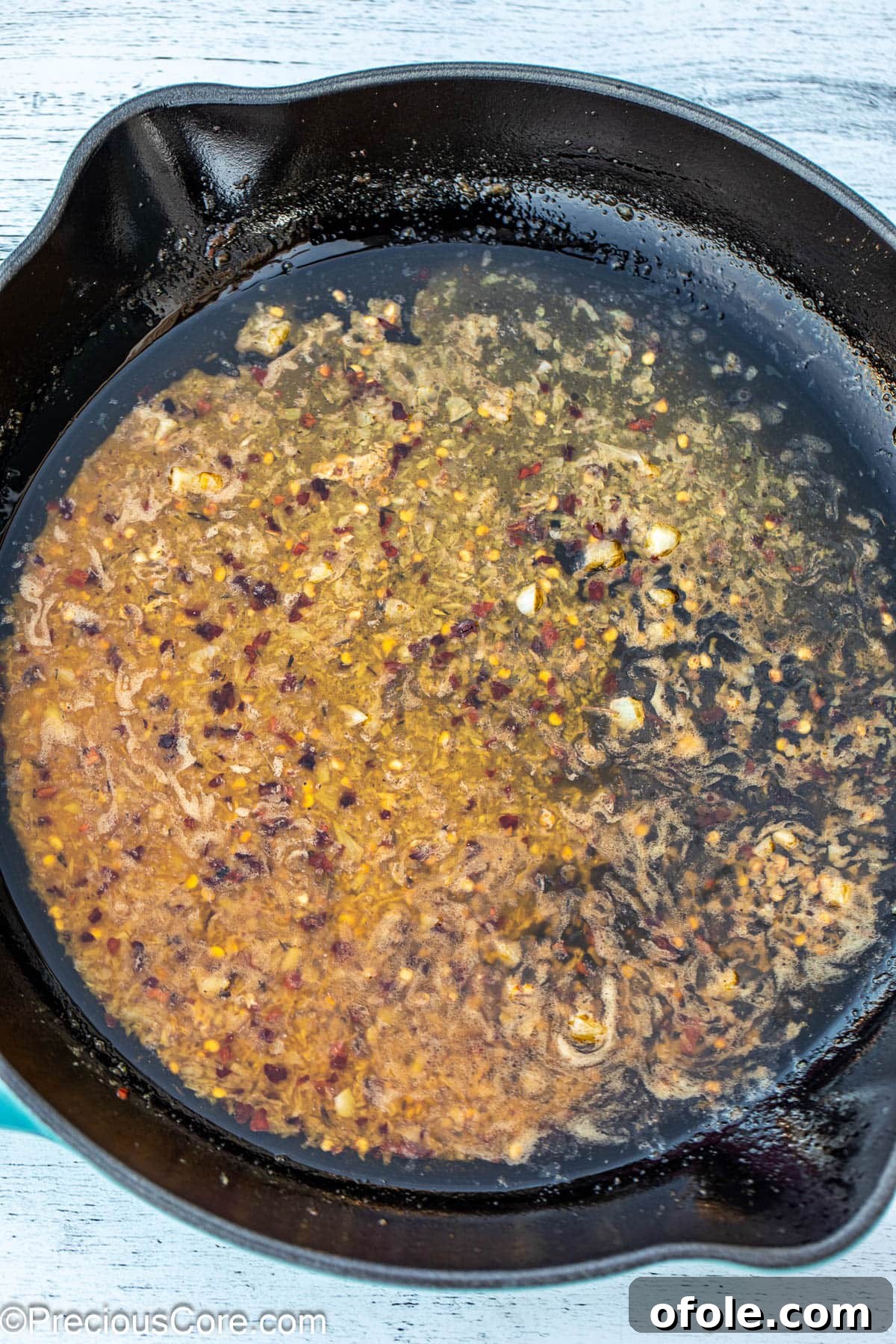 Minced garlic cloves sizzling in a pool of golden melted butter in a skillet, filling the air with aroma.