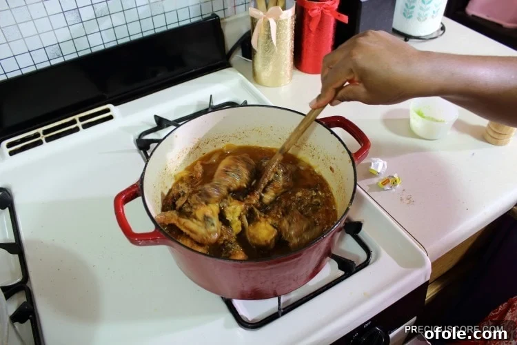 Ultimate Poulet DG Recipe 14 Person stirring a Dutch oven of chicken.