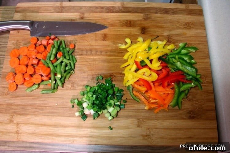 Ultimate Poulet DG Recipe 16 Colorful chopped vegetables on a wooden cutting board.