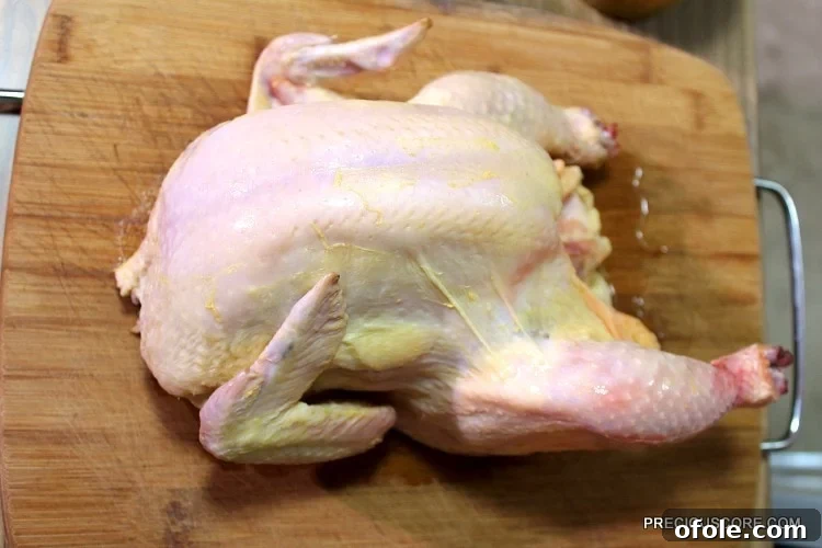 Ultimate Poulet DG Recipe 6 Whole chicken on a wooden cutting board.