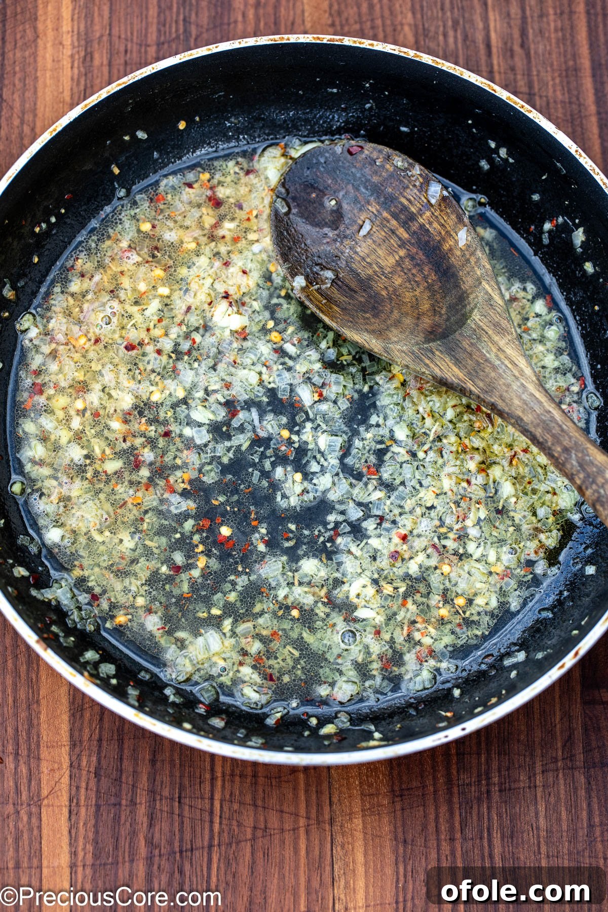 White wine sauce with garlic and shallots in a skillet.