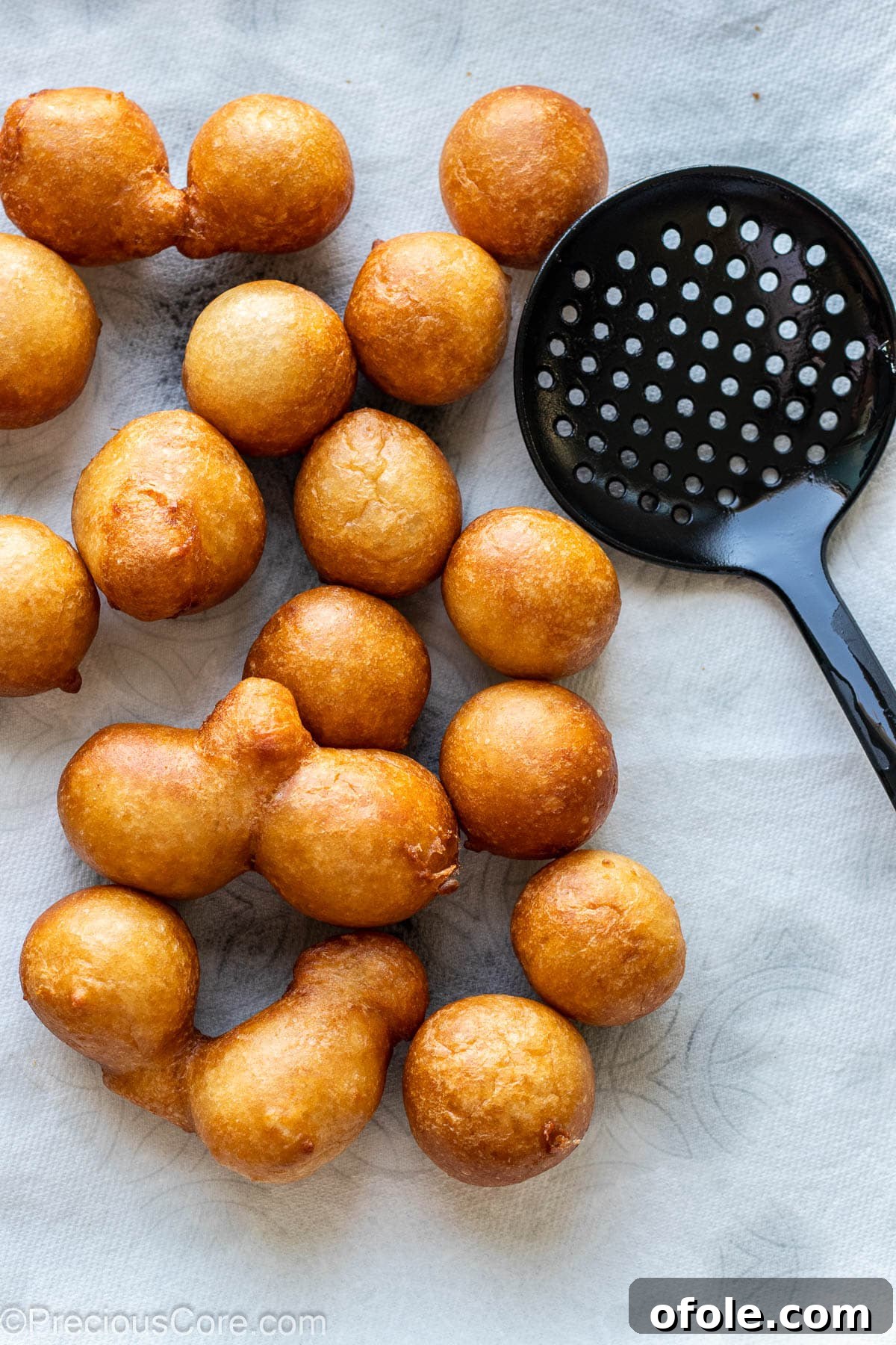 Homemade Fluffy Puff Puff 12 Freshly fried Puff Puff draining on paper towels on a tray, ready to be enjoyed.
