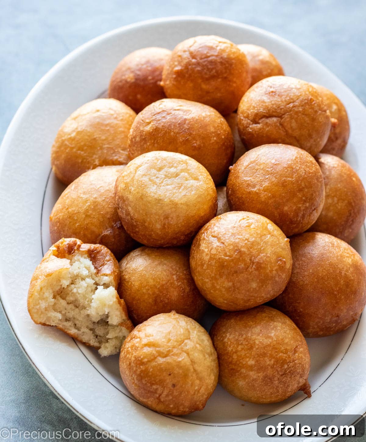 Homemade Fluffy Puff Puff 4 Three Puff Puff balls on a tray, one cut open to reveal its airy, fluffy interior.