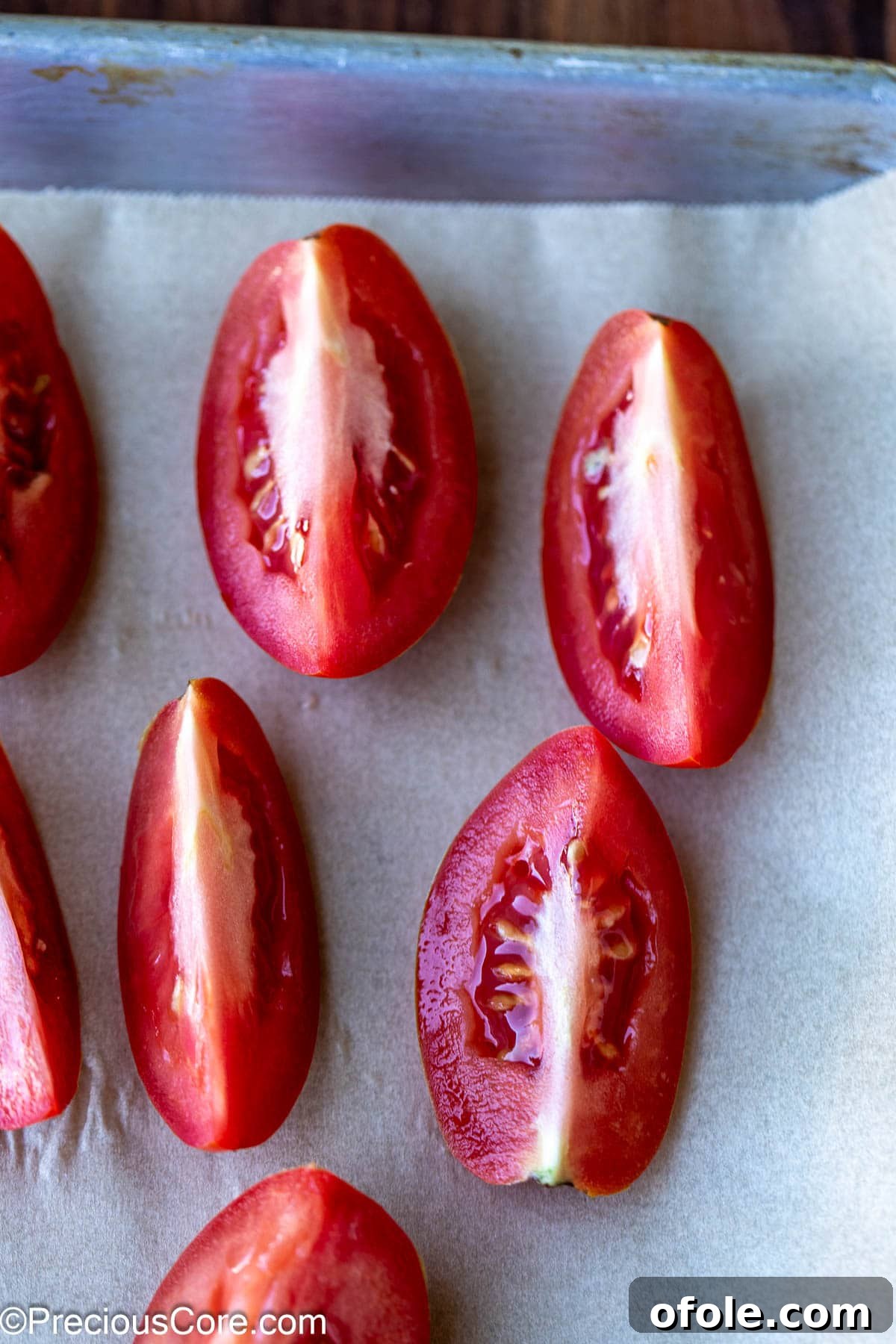 Slow Roasted Tomato Pizza Sauce 4 Roma tomatoes cut into quarters laid out on parchment paper on a baking sheet.