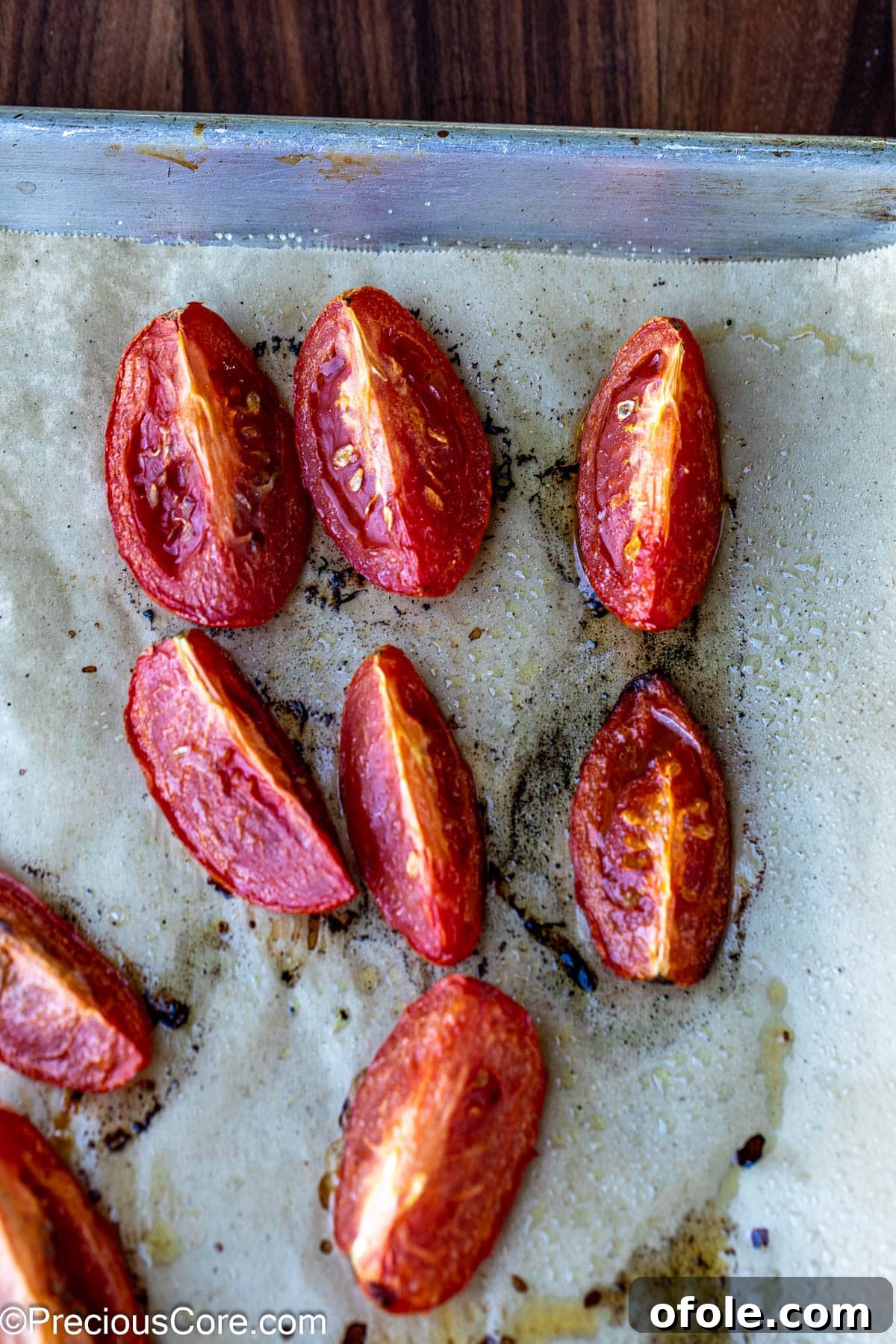 Slow Roasted Tomato Pizza Sauce 6 Golden-brown roasted tomatoes cooling on a baking sheet lined with parchment paper, fresh from the oven.