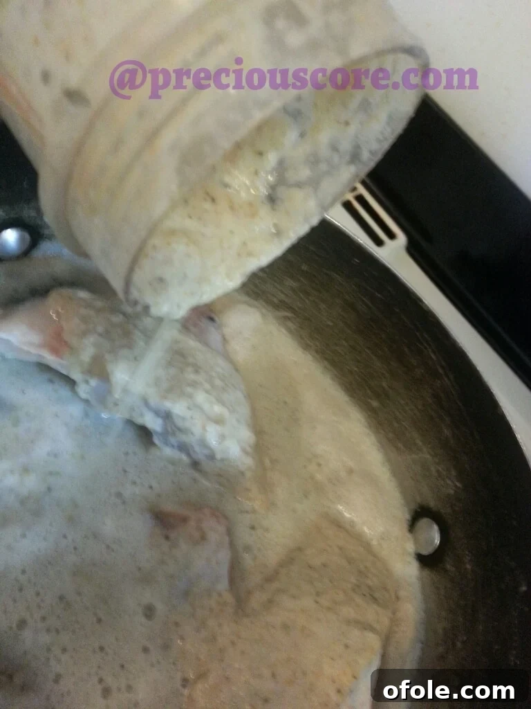 Blended spices and aromatics being poured into the pot with the fish