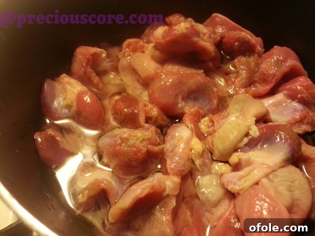 Flavorful Peppered Gizzard Delight 4 Chicken gizzards simmering in a saucepan with water