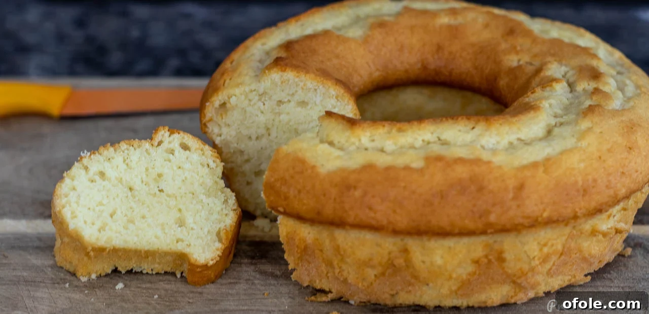 Yogurt cake on cutting board with a slice already removed, showcasing its moist interior.