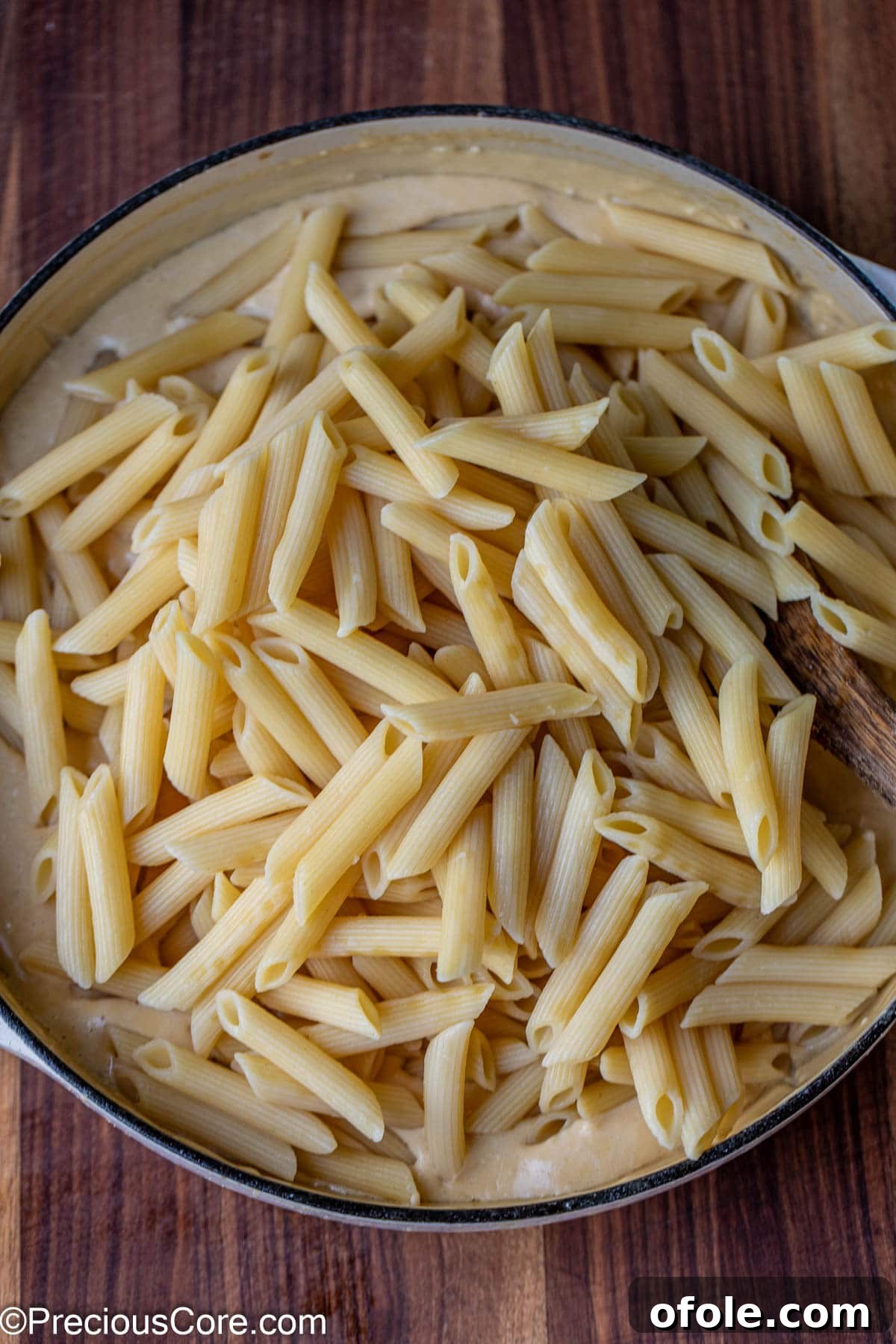 Parmesan Chicken Pasta with Garlic Cream Sauce 12 Cooked pasta being tossed into a pot of white creamy sauce, ensuring full coverage.