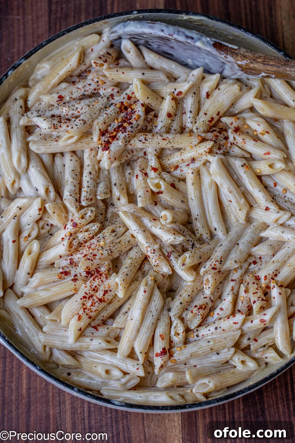 Parmesan Chicken Pasta with Garlic Cream Sauce 13 A pot of creamy penne pasta, generously sprinkled with crushed red pepper flakes and black pepper.