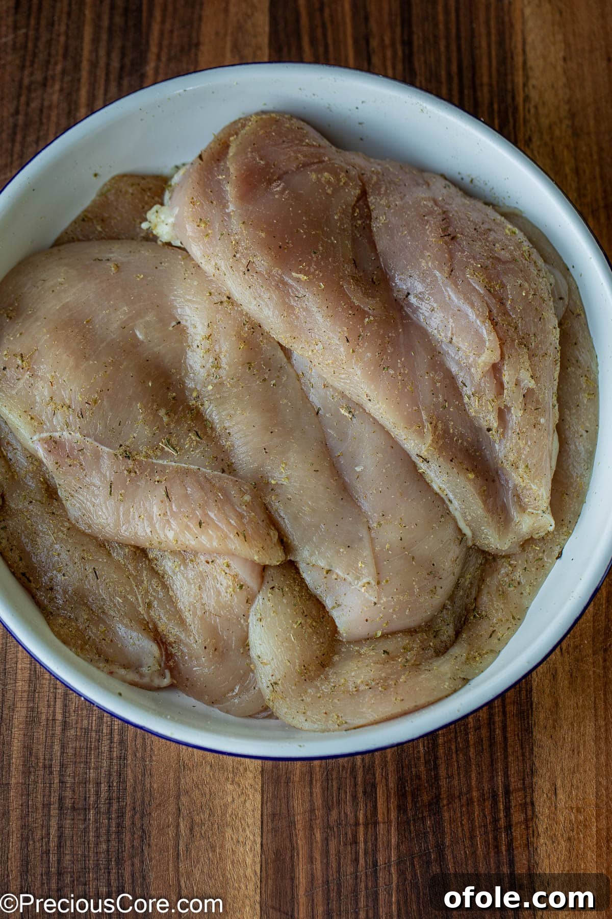 Parmesan Chicken Pasta with Garlic Cream Sauce 6 Seasoned chicken breasts neatly arranged in a white bowl, ready for cooking.