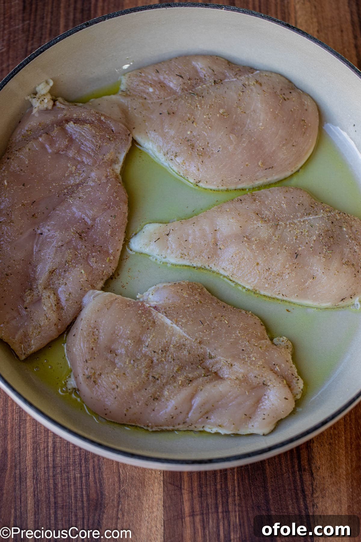 Parmesan Chicken Pasta with Garlic Cream Sauce 7 Raw seasoned chicken breasts being added to a hot pot with olive oil.