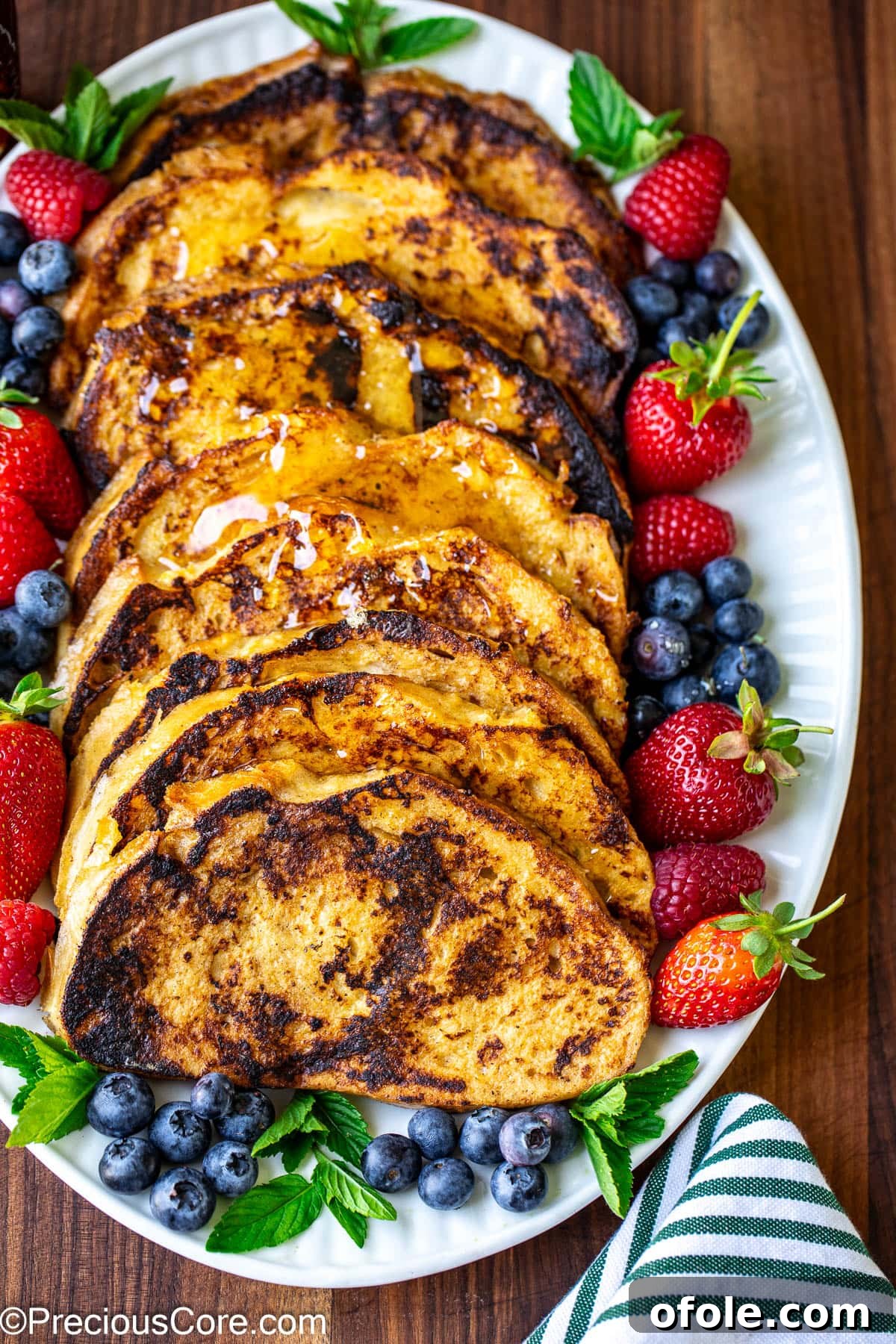 Elevated Sourdough French Toast 2 Perfectly golden slices of Sourdough French Toast arranged on a pristine white oval plate, ready to be served.